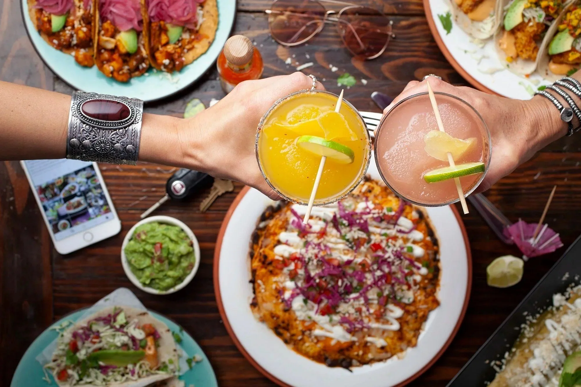 Friends toasting cocktails over a Mexican restaurant table spread, restaurant photography in Los Angeles and Orange County