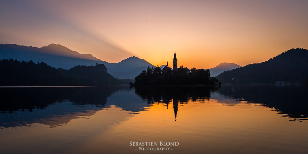 The sun showing its first rays above Lake Bled and the church on the island