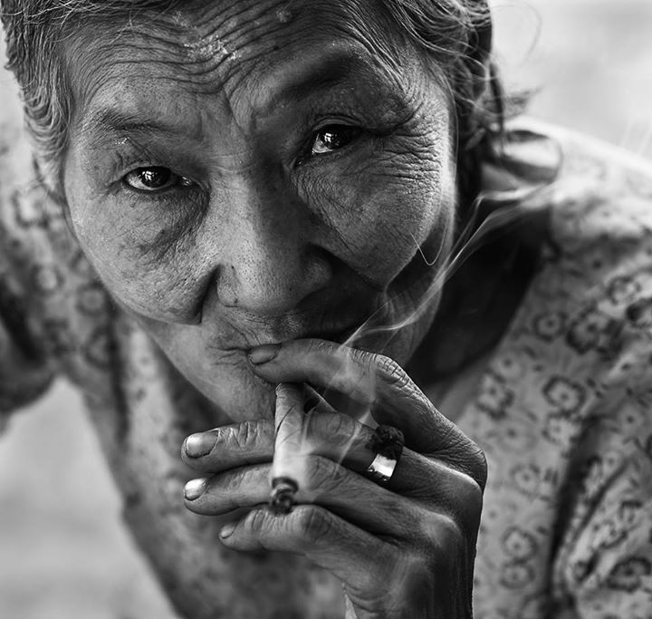 An old lady smoking a hand rolled cigarette in Myanmar
