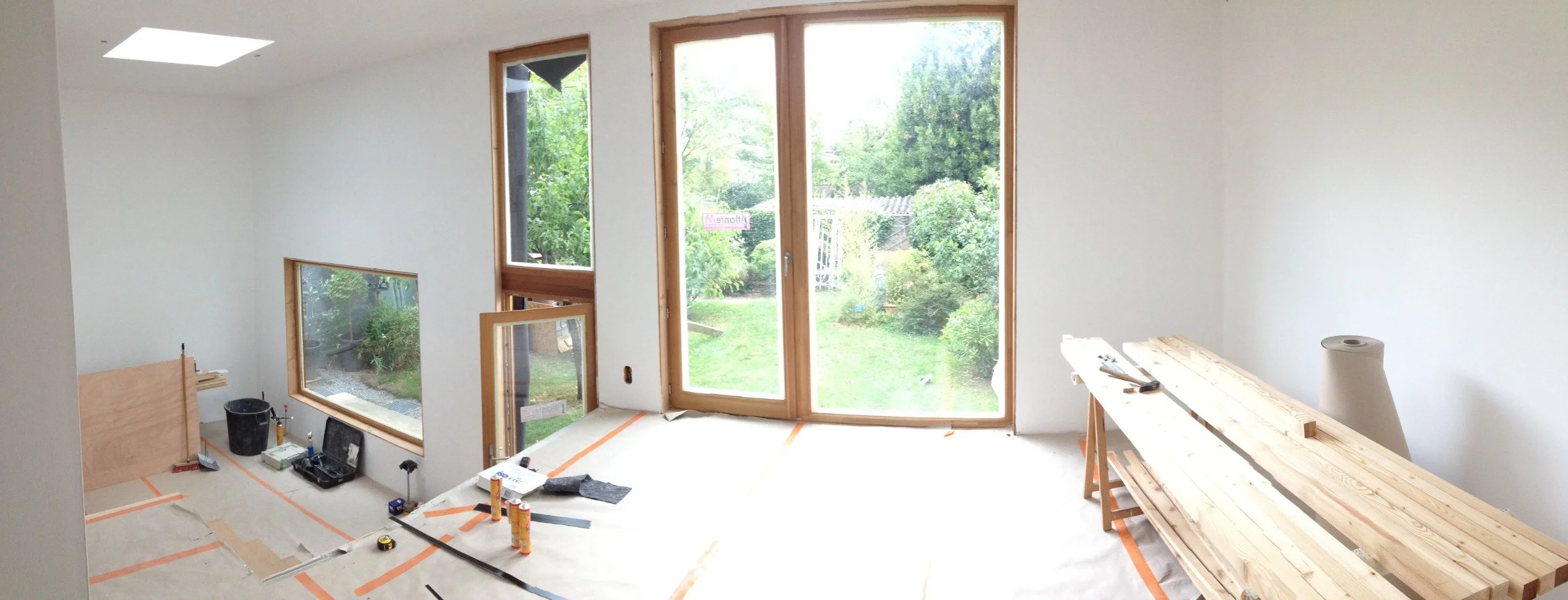 Chantier de l'extension ACAJOU à Nantes : aménagement intérieur de la salle à manger, grandes baies en bois ouvertes sur le jardin