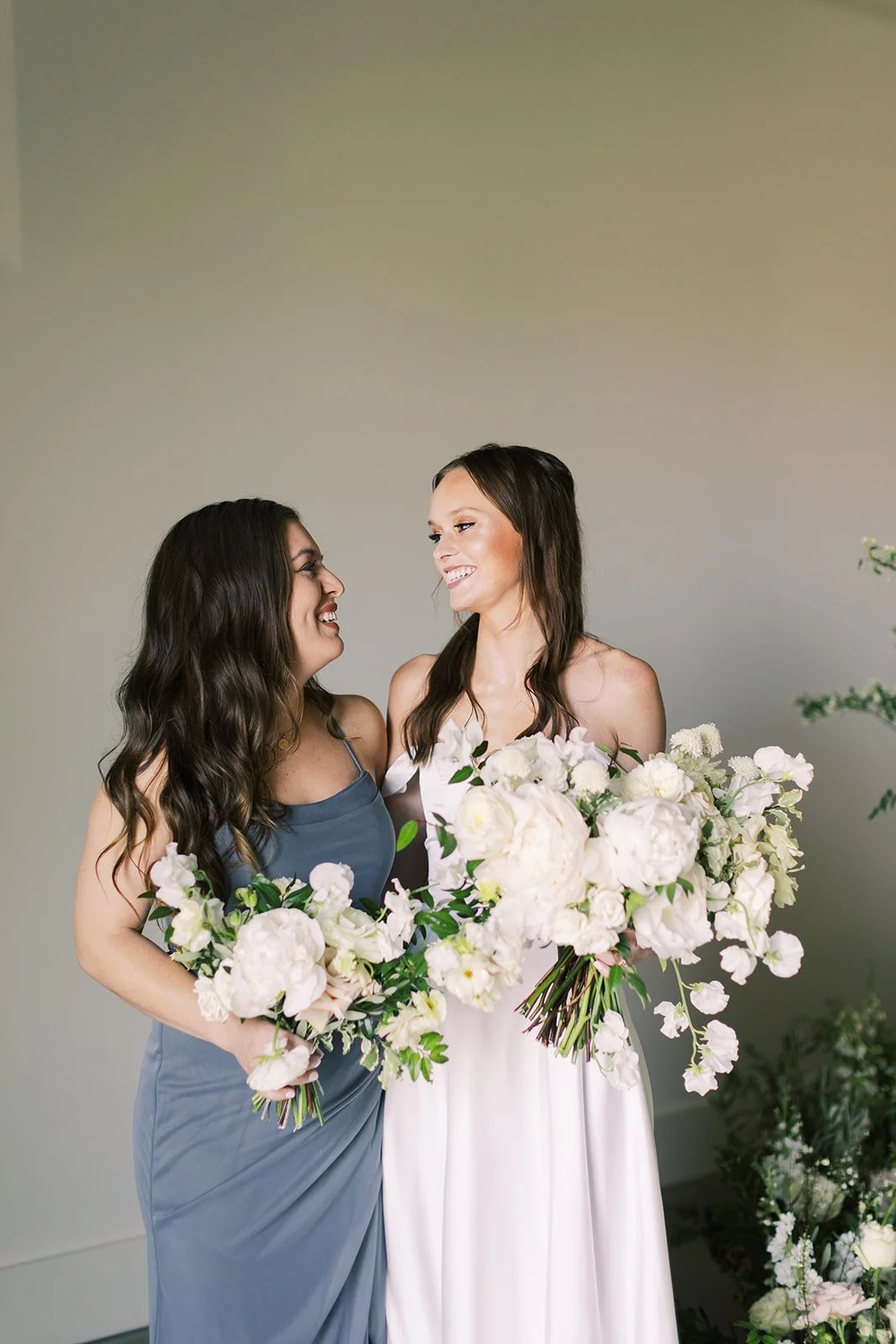 Bridal party florals of white garden roses, peonies, ranunculus, sweet peas, scabiosa, butterfly ranunculus and dark greenery in floral hues of white, cream, and blush. Designed by Rosemary and Finch in Nashville, TN.