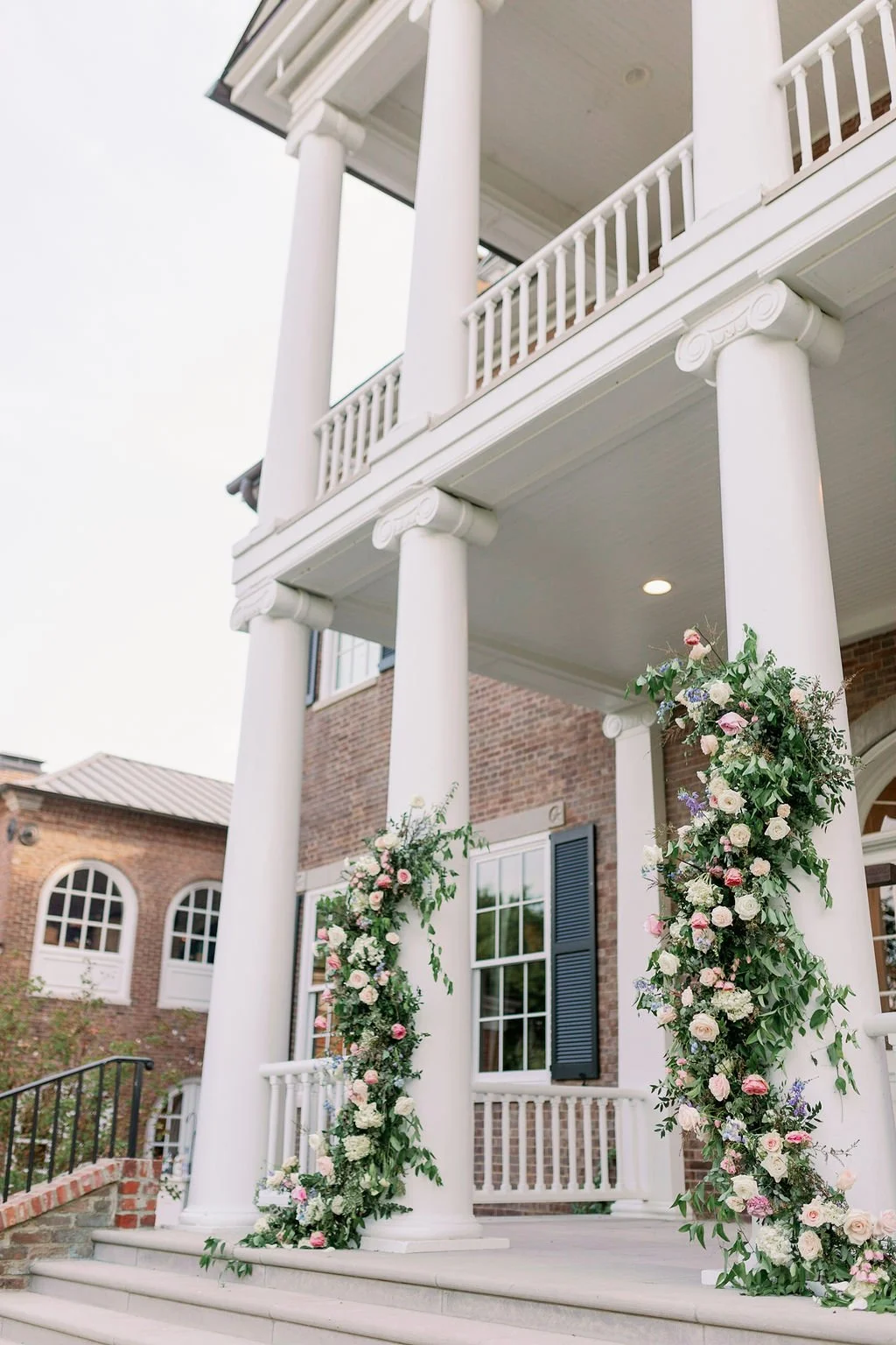 An organic growing arch filled with blush and ivory roses, majolica spray roses, champagne roses, hydrangea, and lush sprawling greenery and accented with low growing aisle markers. Designed by Rosemary & Finch in Nashville, TN.
