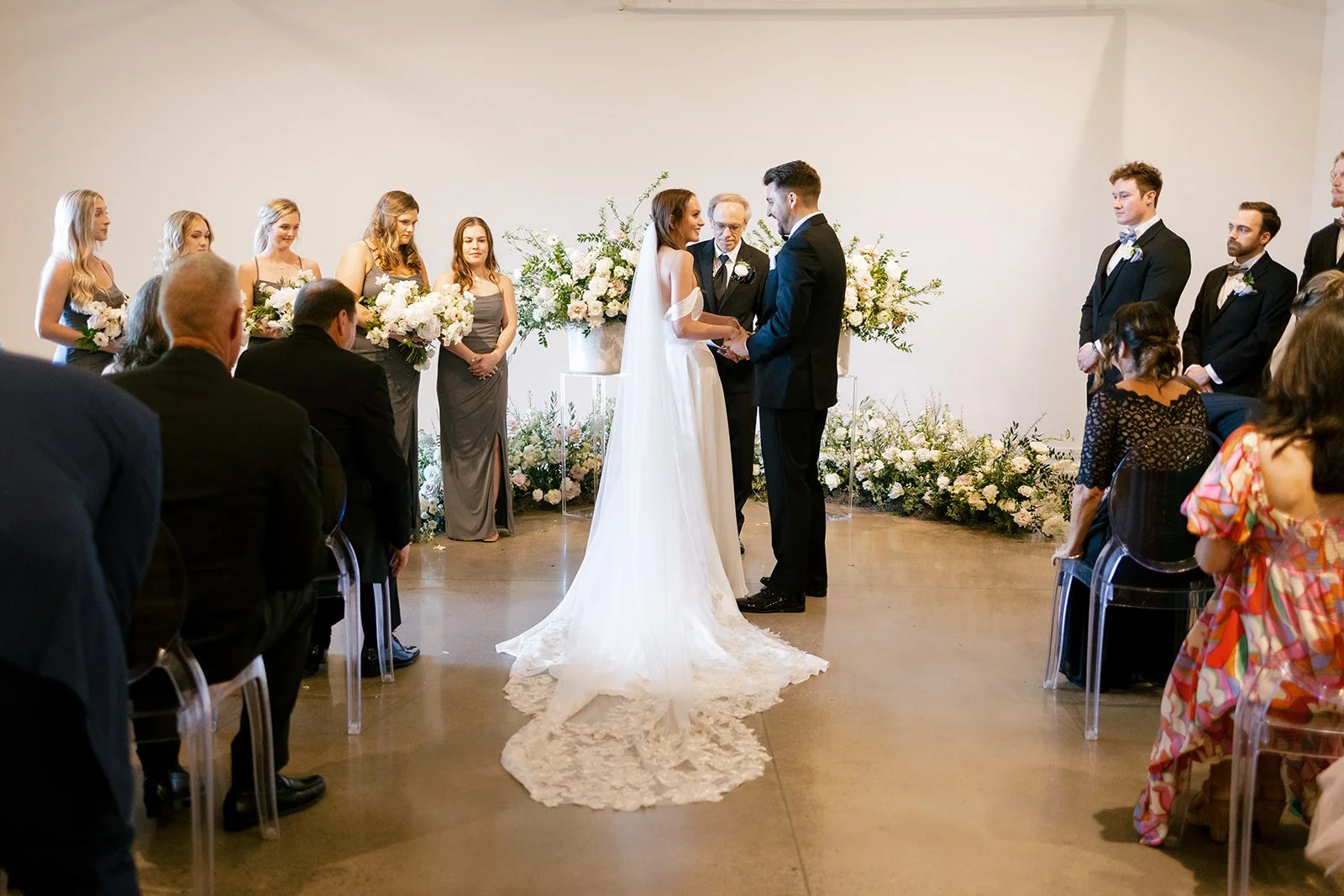 Lush ceremony installation featuring garden urns and meadows with petal heavy roses butterfly ranunculus, delphinium, and Queen Anne’s lace with natural, untamed greenery. Floral hues of white, cream, and blush. Designed by Rosemary and Finch in Nash