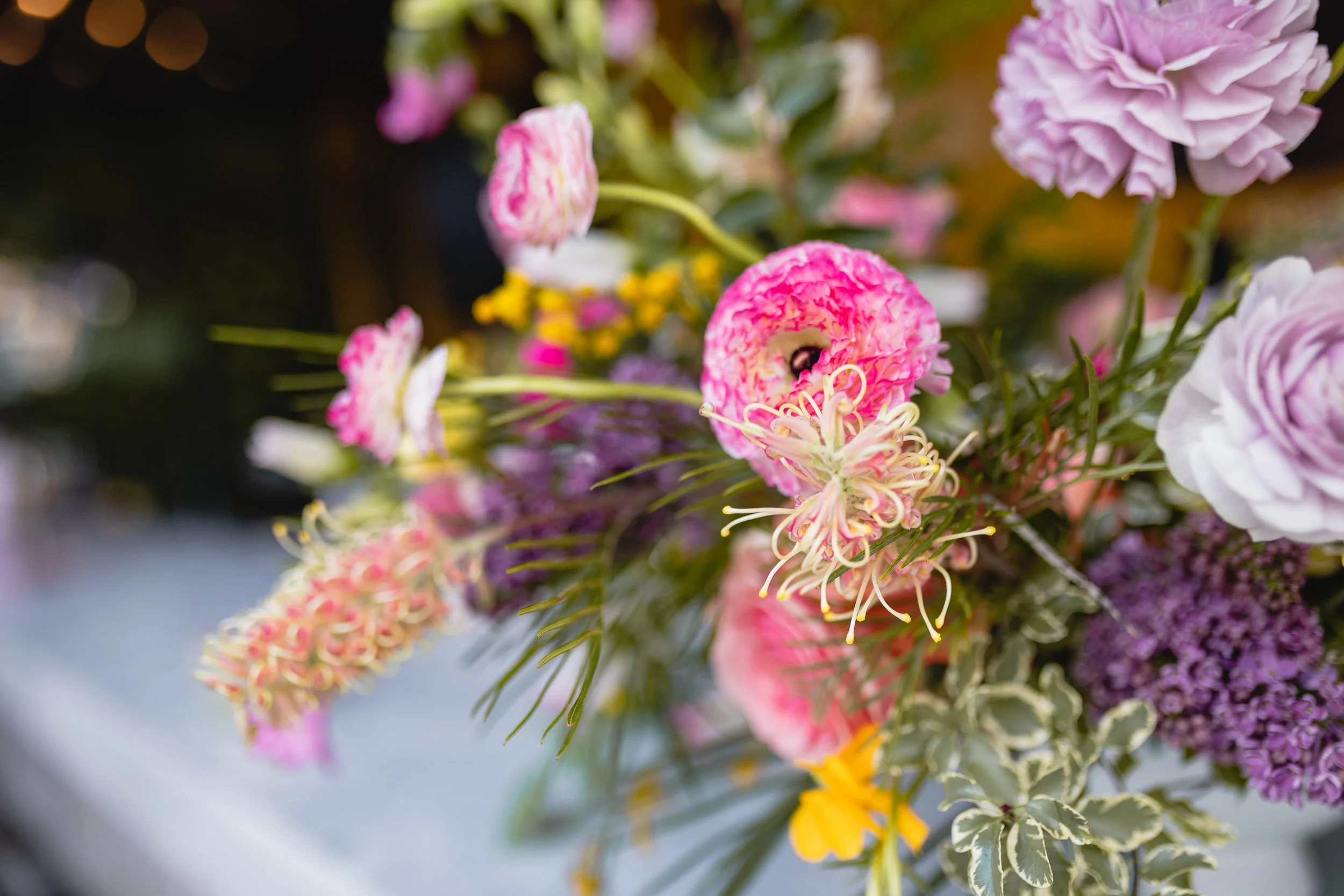 Bright spring floral hues of pink, lavender, coral, magenta, and yellow inspire the event space of Fifth + Broadway in Nashville, TN. Florals composed of roses, ranunculus, sweet peas, butterfly ranunculus, mixed greenery. Design by Rosemary and Finc