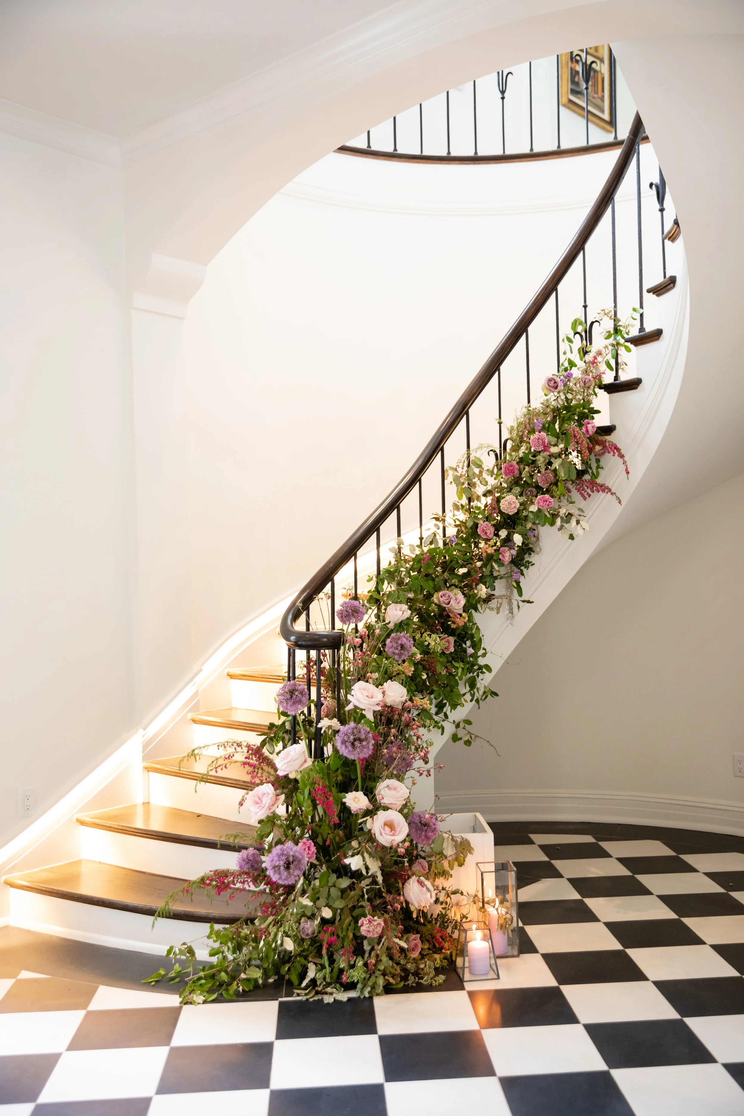 Lush floral installation growing up the staircase with natural greenery, purple globe allium, blush garden roses, and pastel wildflowers. Bridgerton inspired engagement party at  private home in Nashville, TN