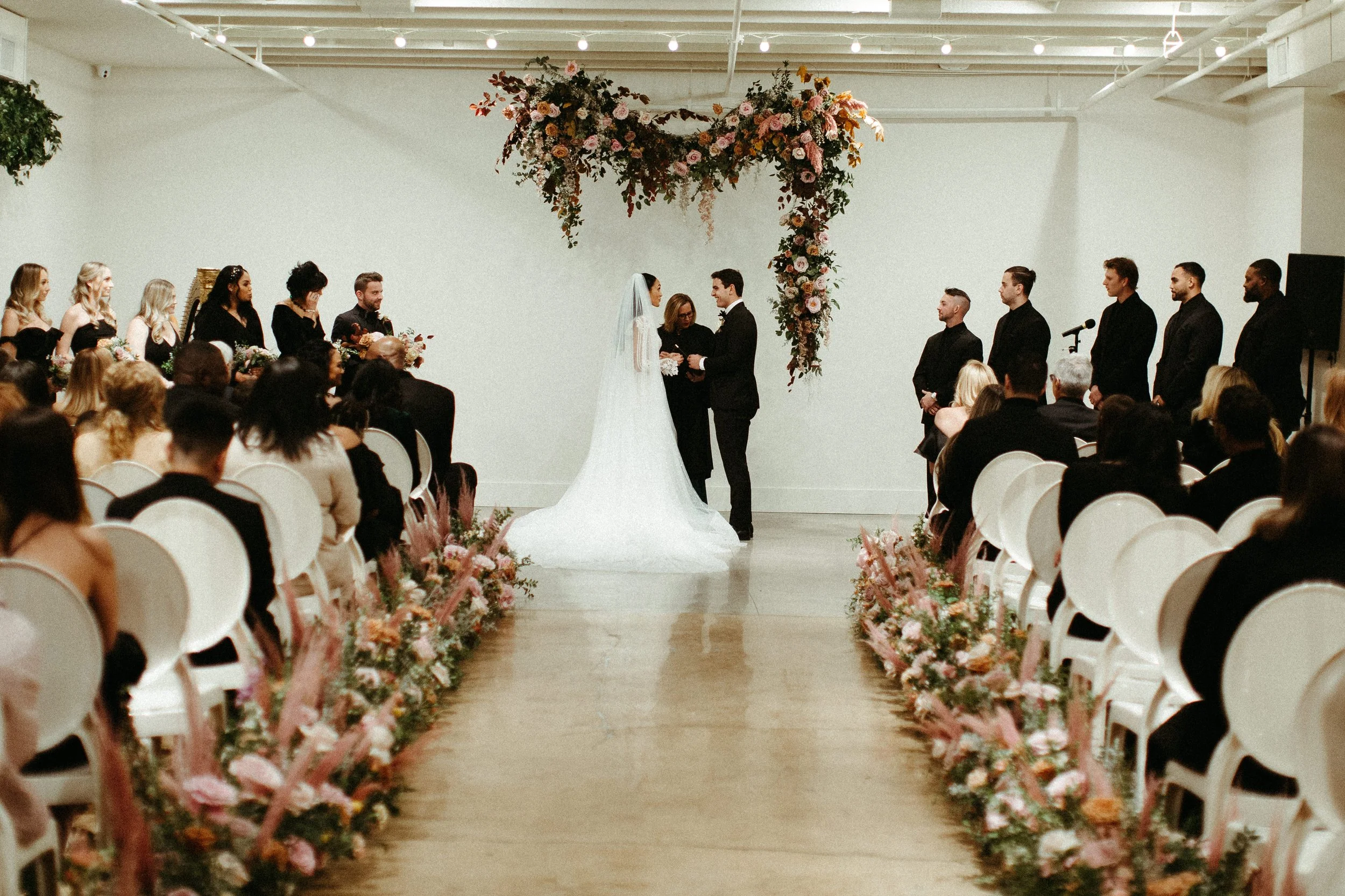 An eye-catching whimsical installation full of petal heavy roses and copper beech was the highlight of this art deco wedding. Terra cotta, burgundy, dusty pink, and other neutral florals warm up this ceremony. Designed by Rosemary and Finch in Nashvi