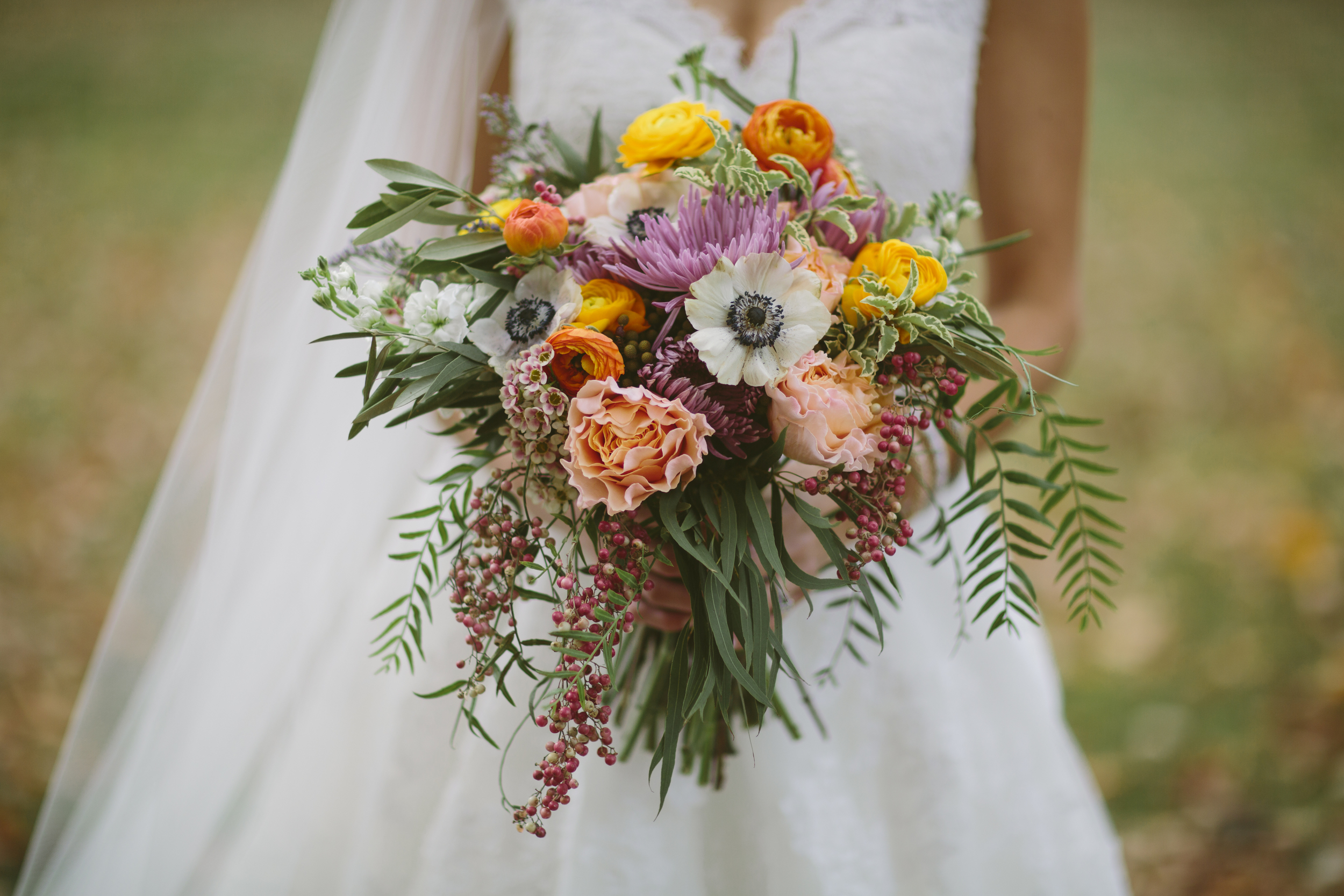 Colorful, bohemian bridal bouquet with anemones, orange ranunculus, peach garden roses, and greenery // Nashville Wedding Flowers