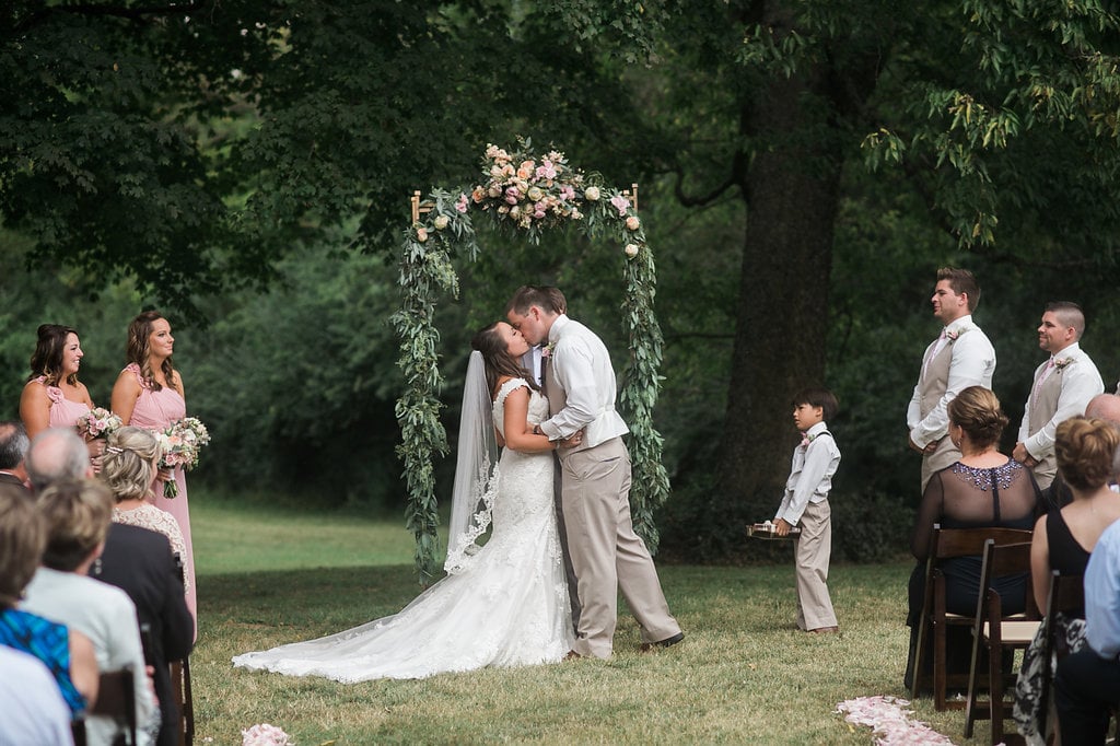 First Kiss under lush floral and greenery arbor // Tennessee Florist