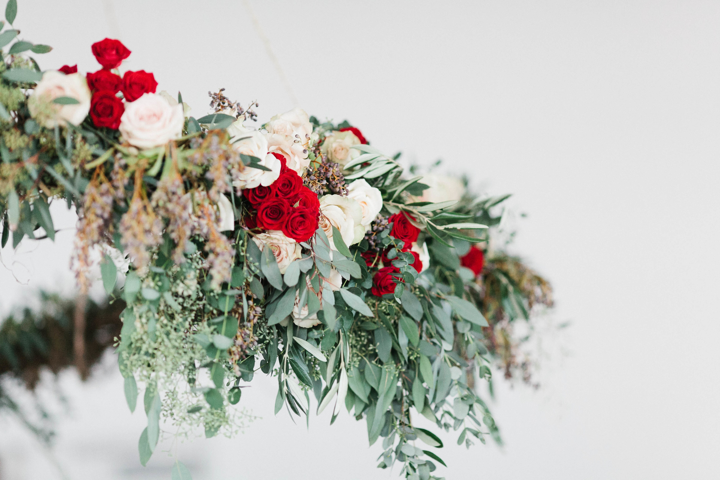 Suspended floral ceremony backdrop with deep red accents