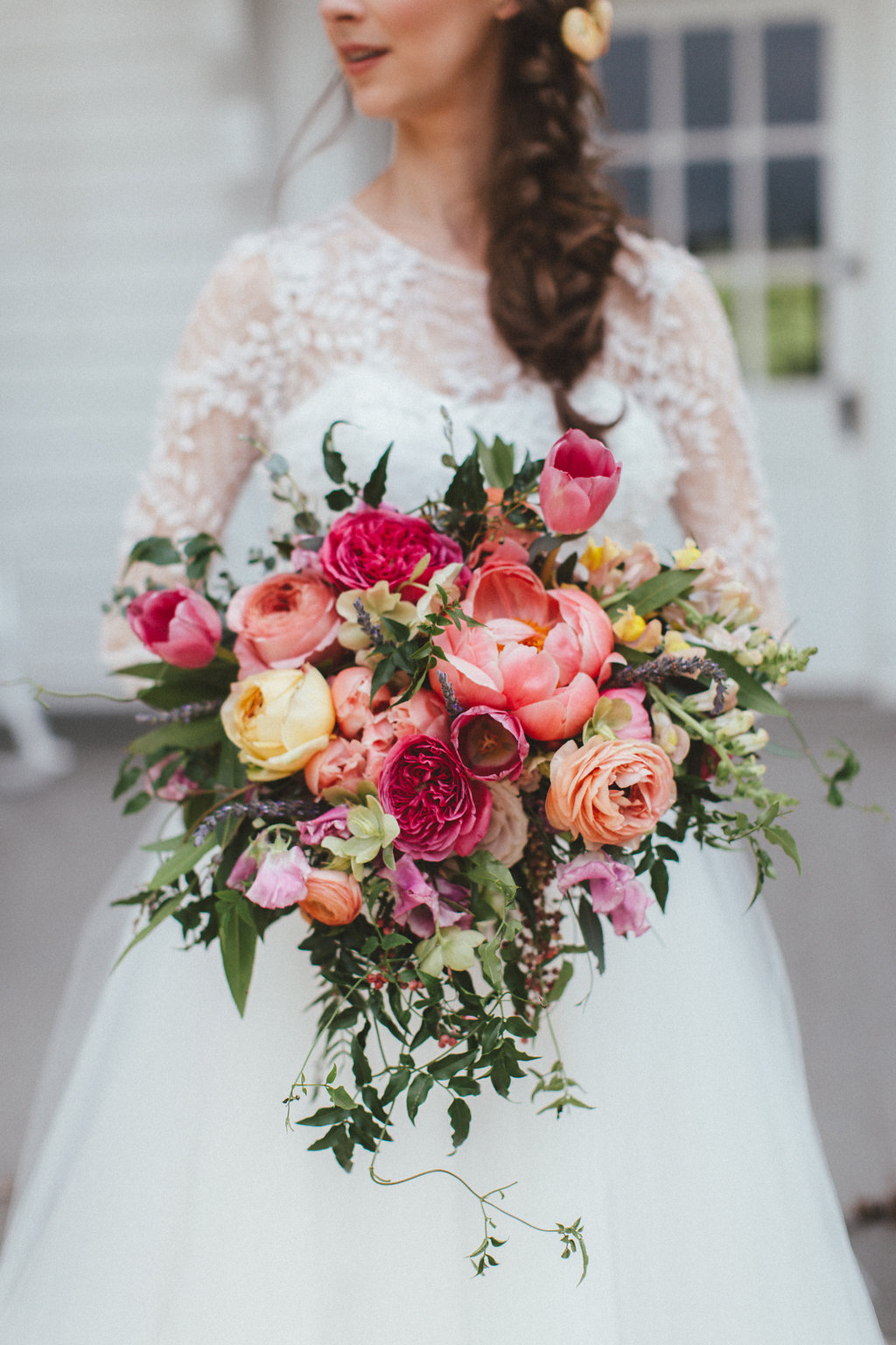 Lush, cascading bridal bouquet with coral peonies, peach ranunculus, and pink tulips // Nashville Wedding Florist