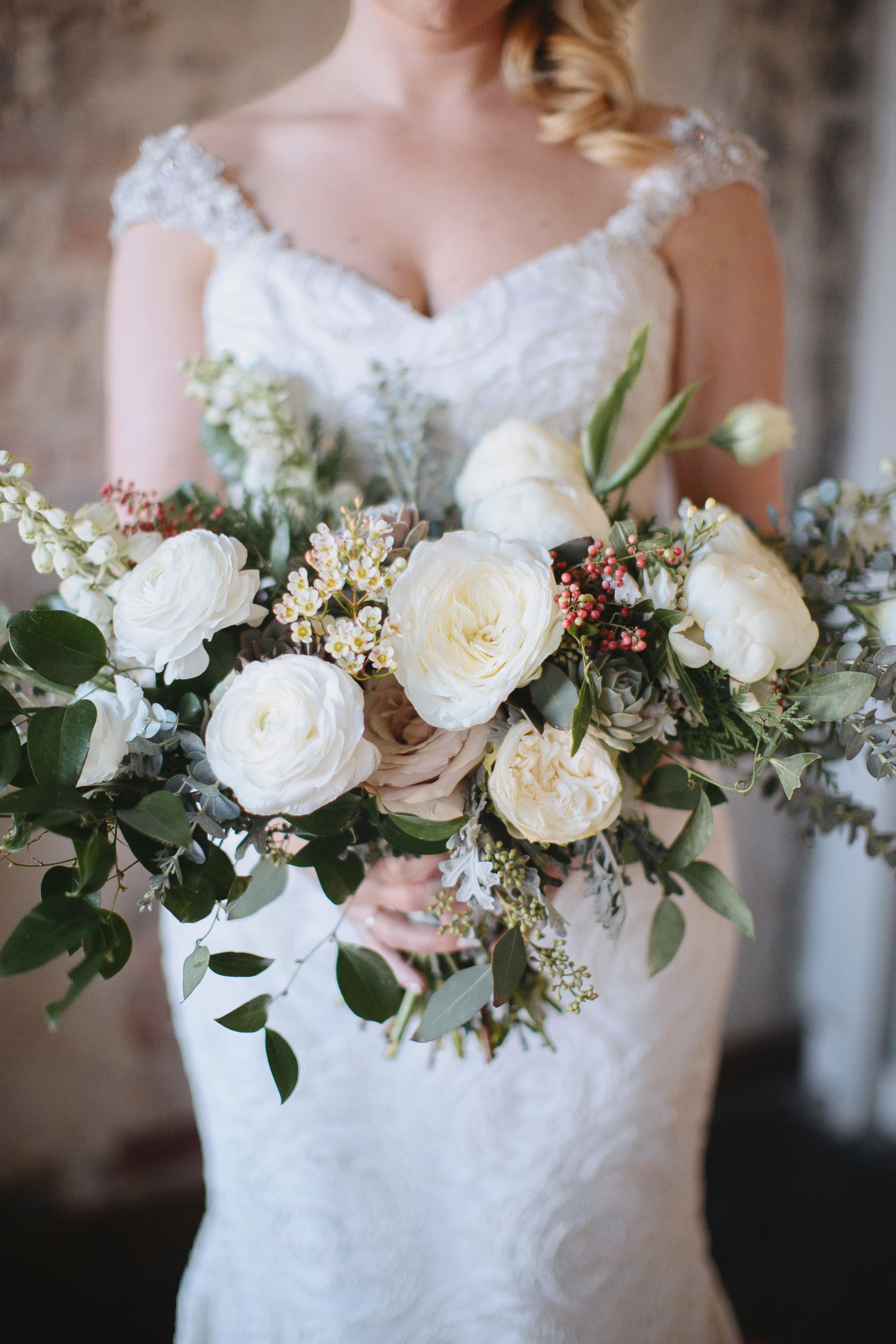Wintry bridal bouquet with all white flowers, natural greenery, and touches of red berries // Nashville Wedding Florist