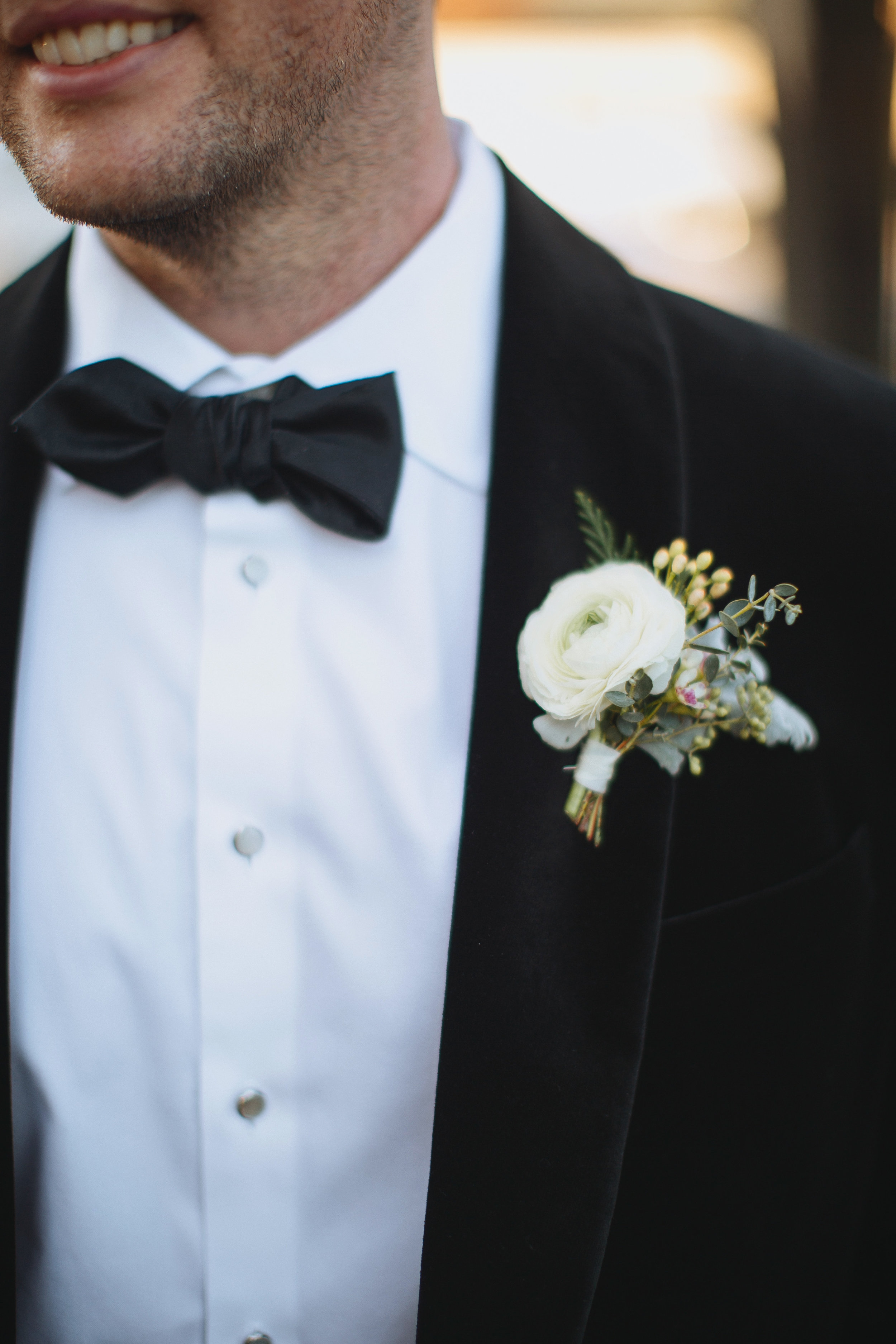Wintry Boutonniere with evergreen, red berries, and a white ranunculus // Nashville Wedding Flowers