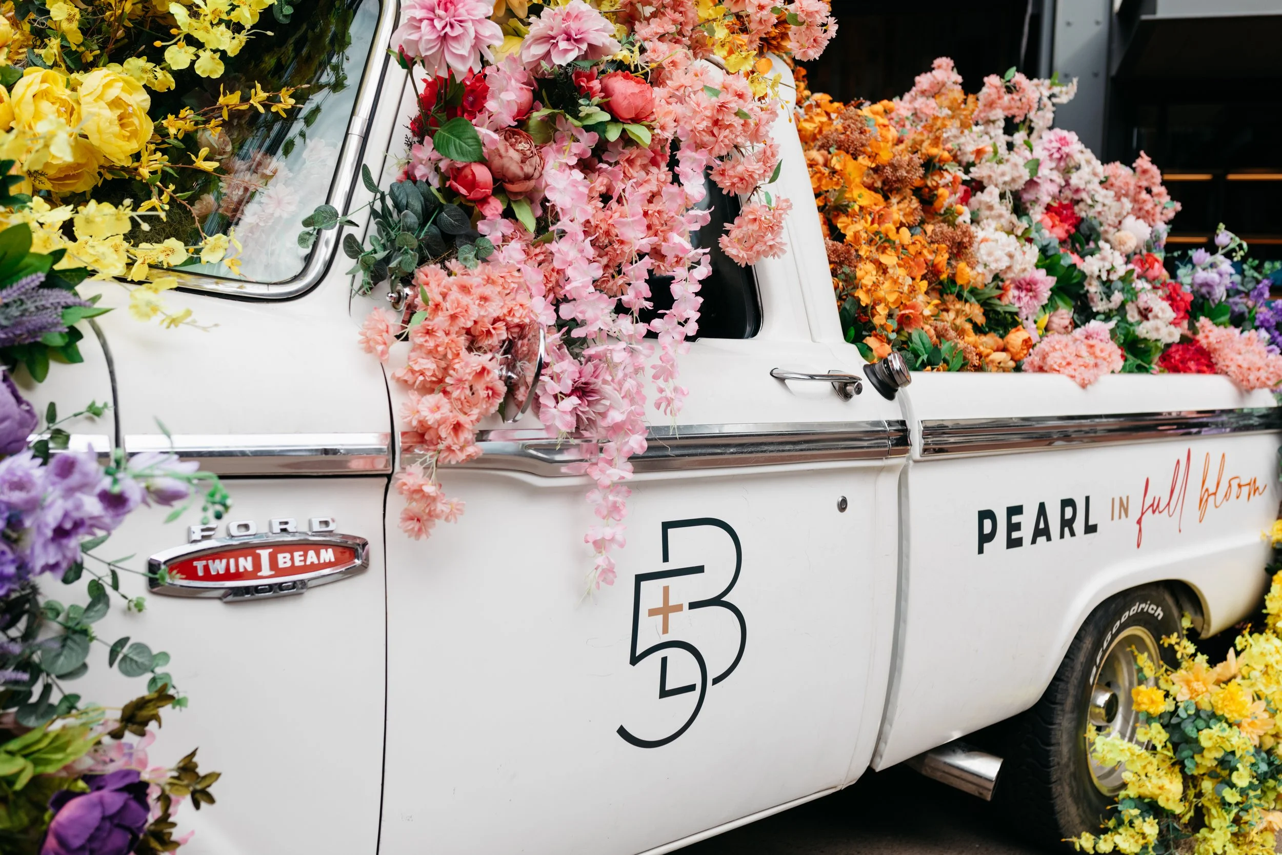 Cheerful pickup truck installation composed of silk floral hues in pink, magenta, lavender, coral, orange, yellow, and mixed greens bring to life this spring Fifth + Broadway event in Nashville, TN. Design by Rosemary and Finch.