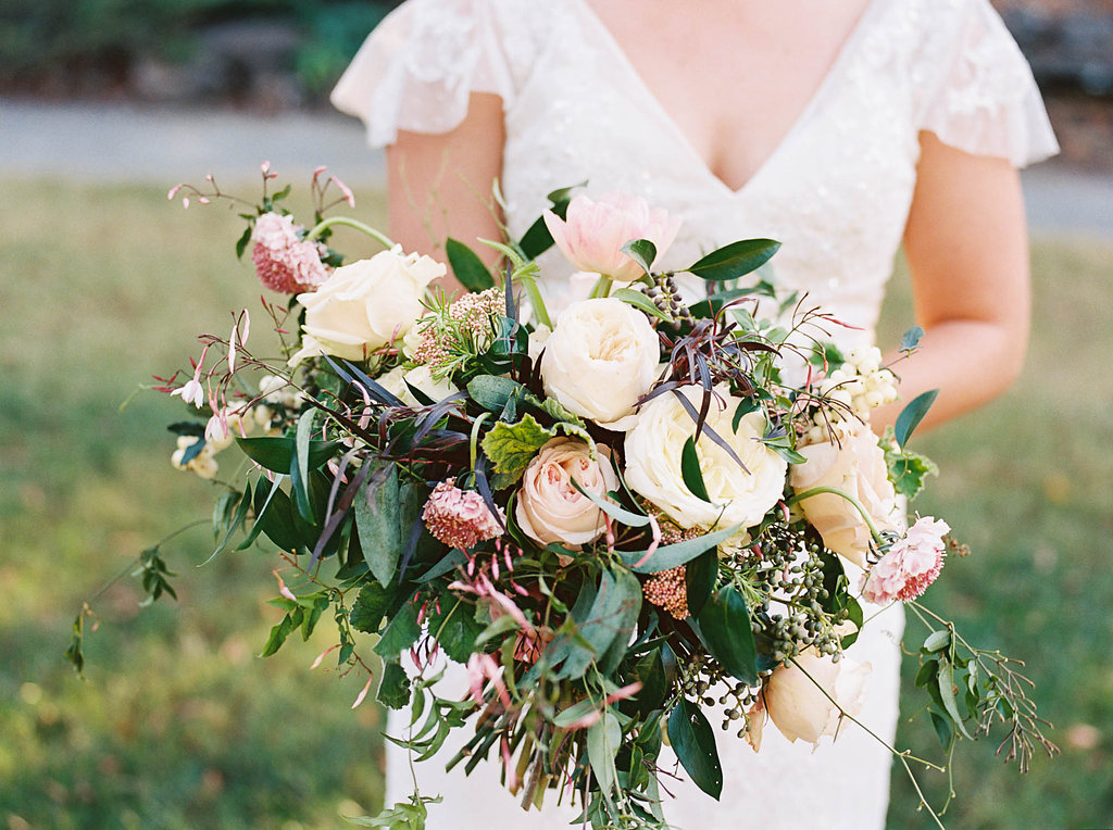 Lush, natural bridal bouquet with garden roses, tulips, blush ranunculus, and greenery in botanical garden // Nashville Wedding Floral Design