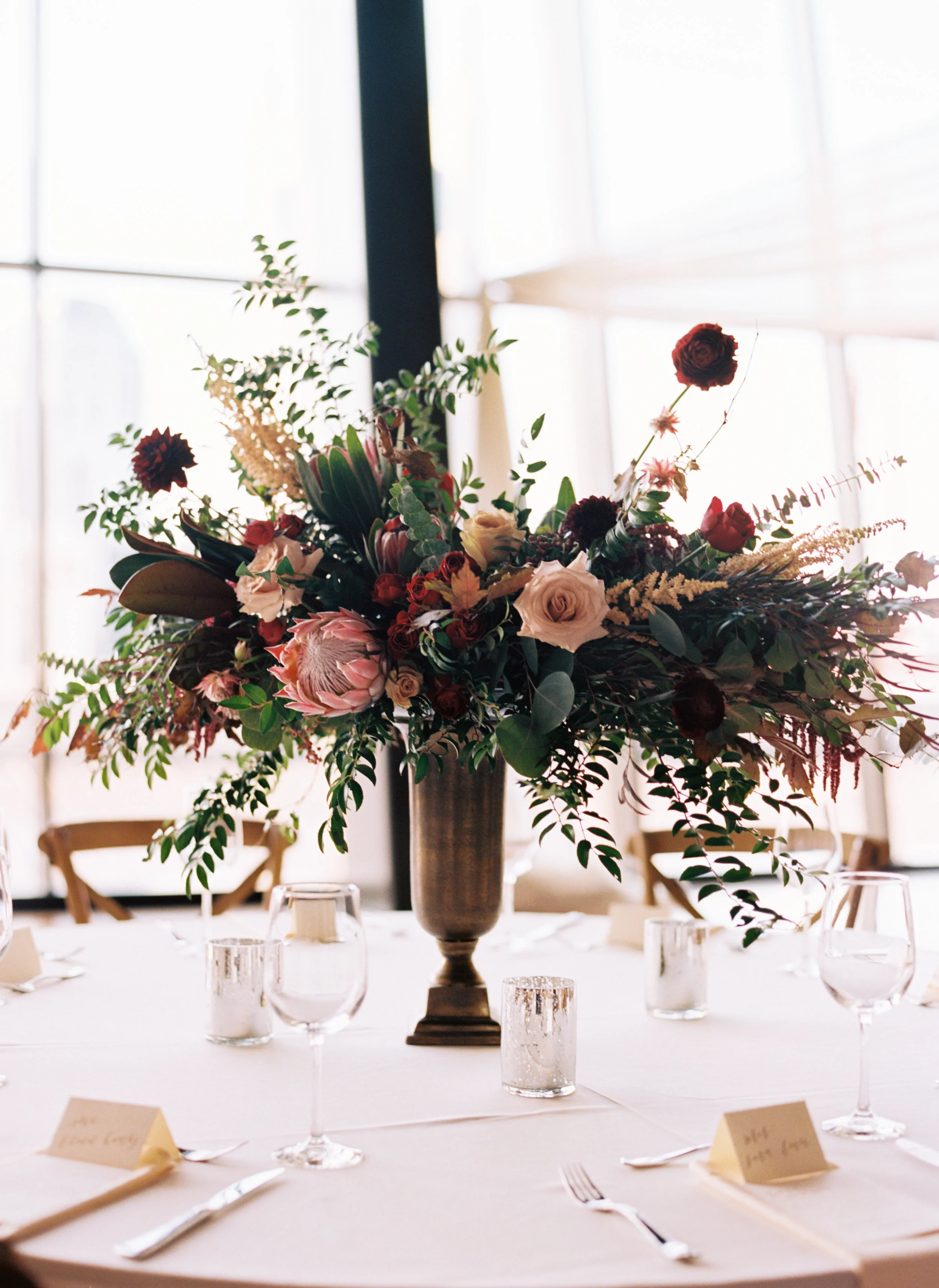 Centerpieces with marsala dahlias, burgundy ranunculus, peach astilbe, protea, and natural greenery // Nashville Wedding Florist // Country Music Hall of Fame
