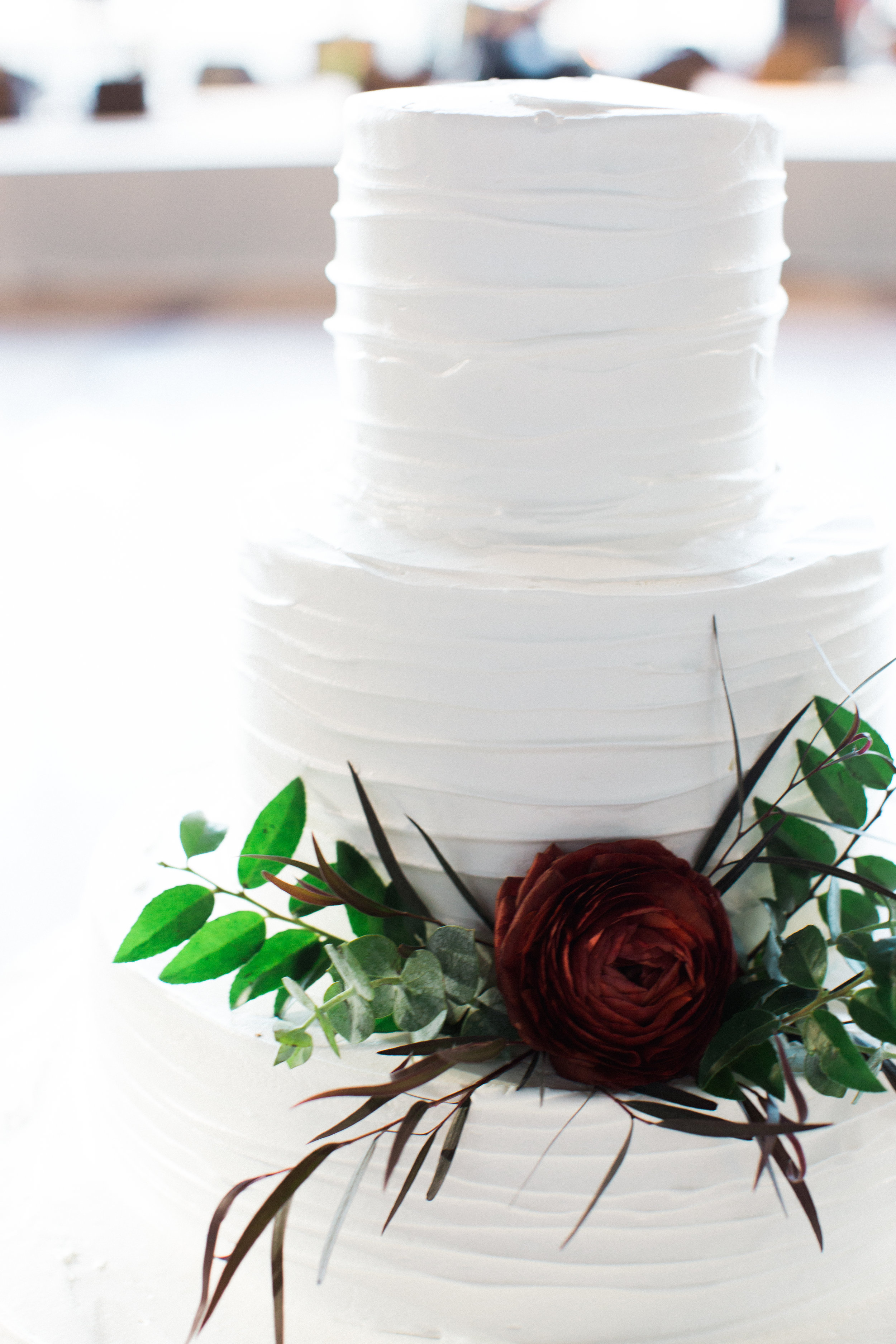 Classic white cake with a single burgundy ranunculus and touches of green // Nashville Wedding Florals