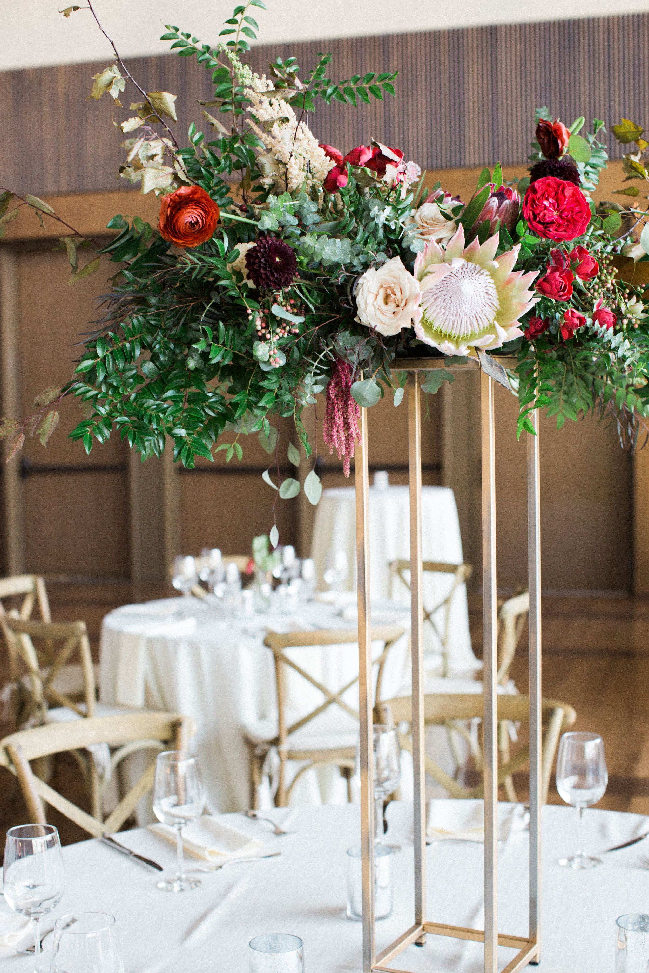 Lush, untamed elevated centerpiece with king protea, marsala dahlias, soft peach astilbe, and natural greenery // Nashville Wedding Floral Design