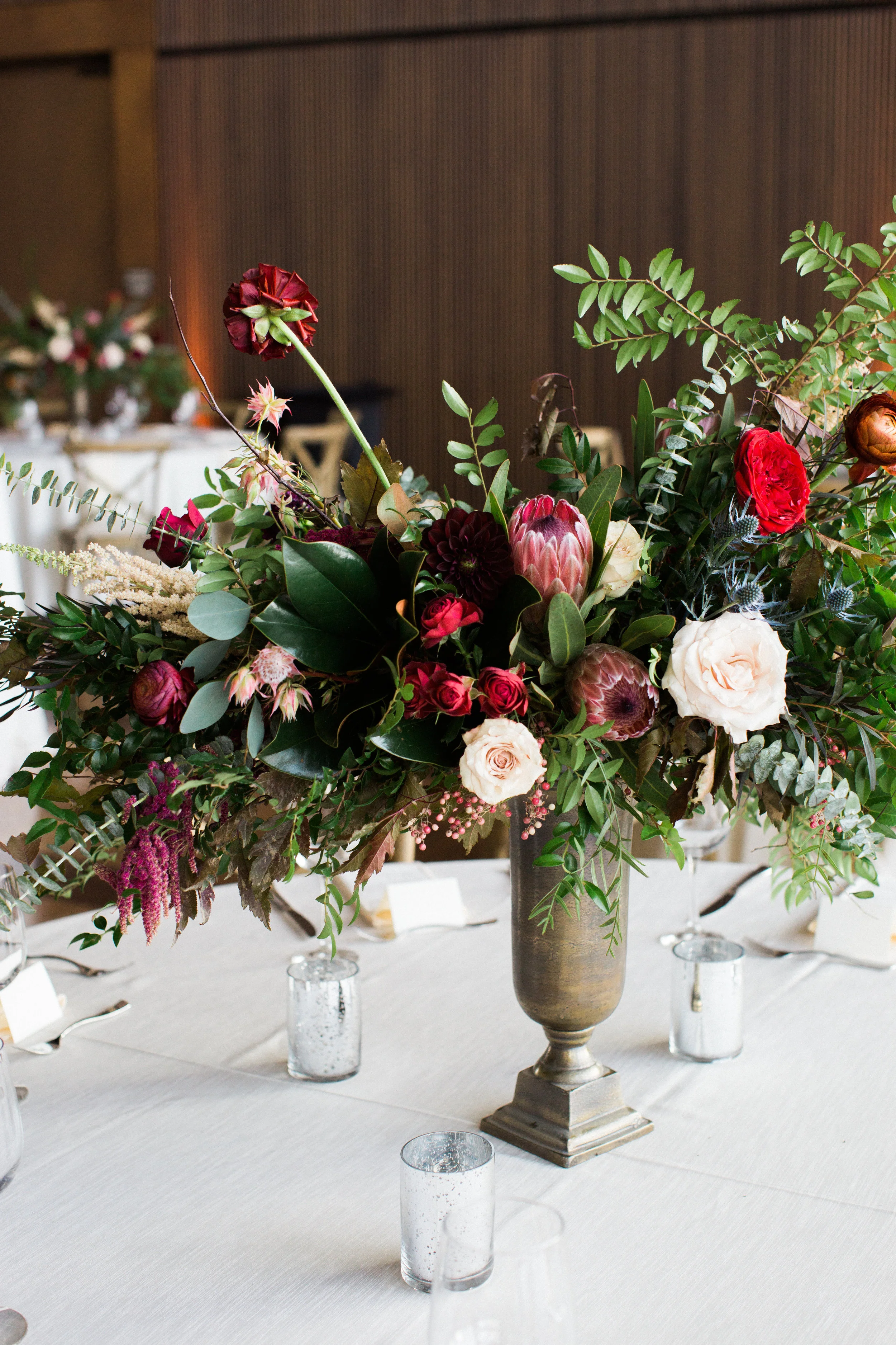 Lush, untamed elevated centerpiece with king protea, marsala dahlias, soft peach astilbe, and natural greenery // Nashville Wedding Floral Design