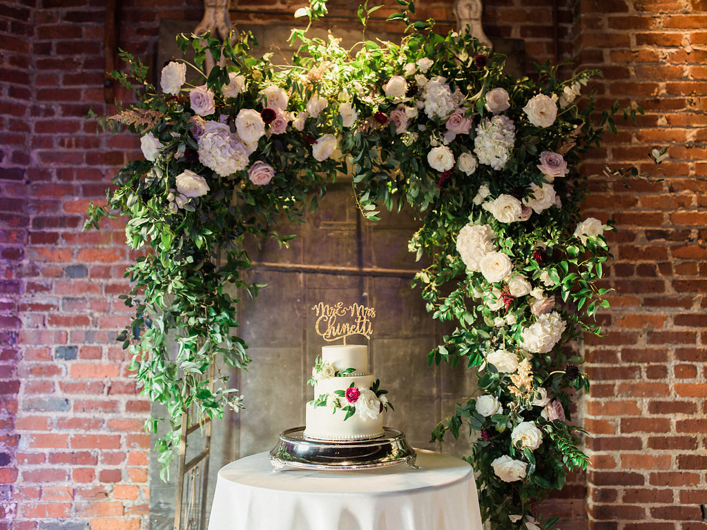 Lush garden arch with natural greenery behind the cake // Nashville Wedding Floral Design