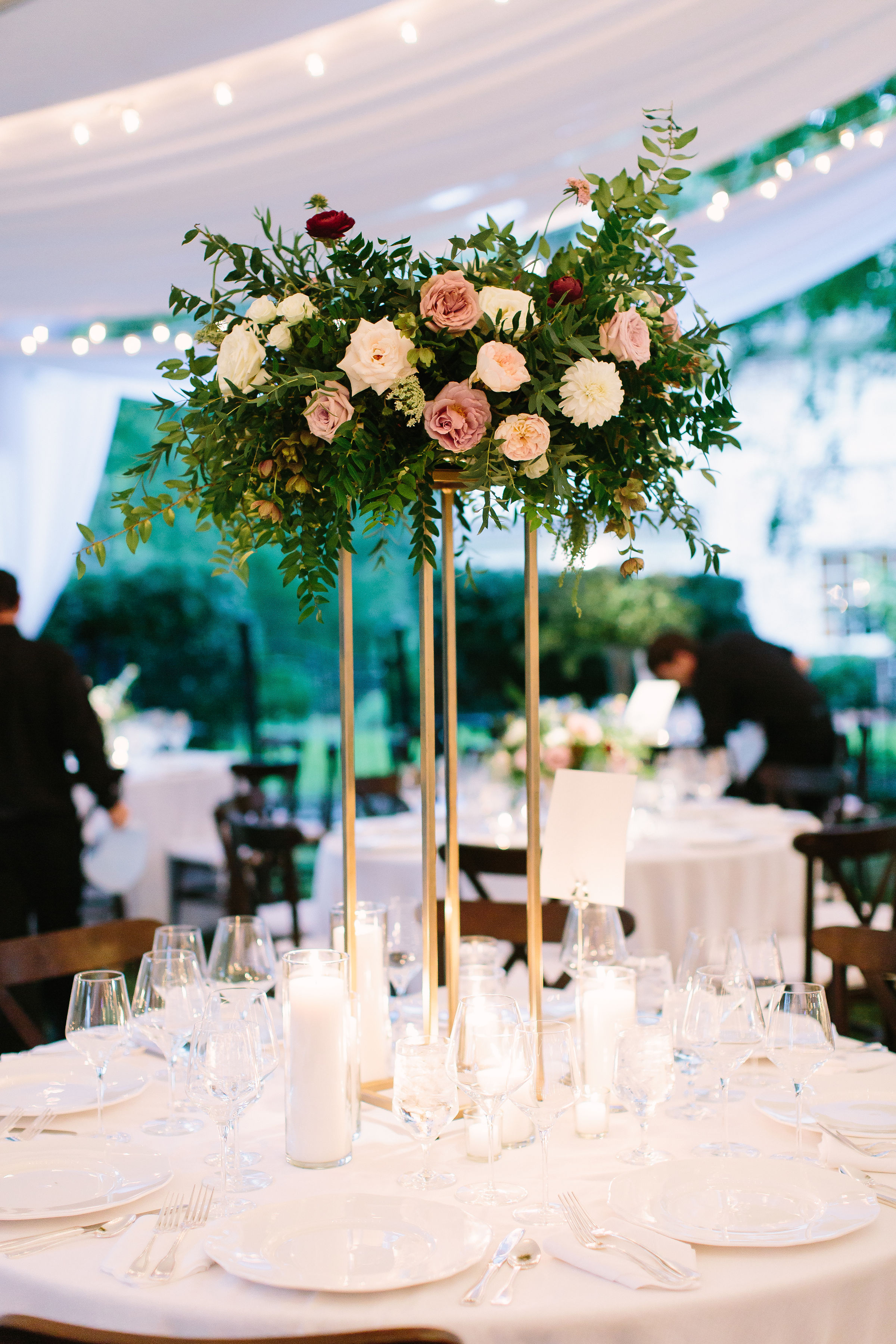 Slender gold stand overflowing with an elevated arrangement of lush, trailing greenery, garden roses and ranunculus in hues of mauve, blush, and ivory // Nashville Wedding Flowers