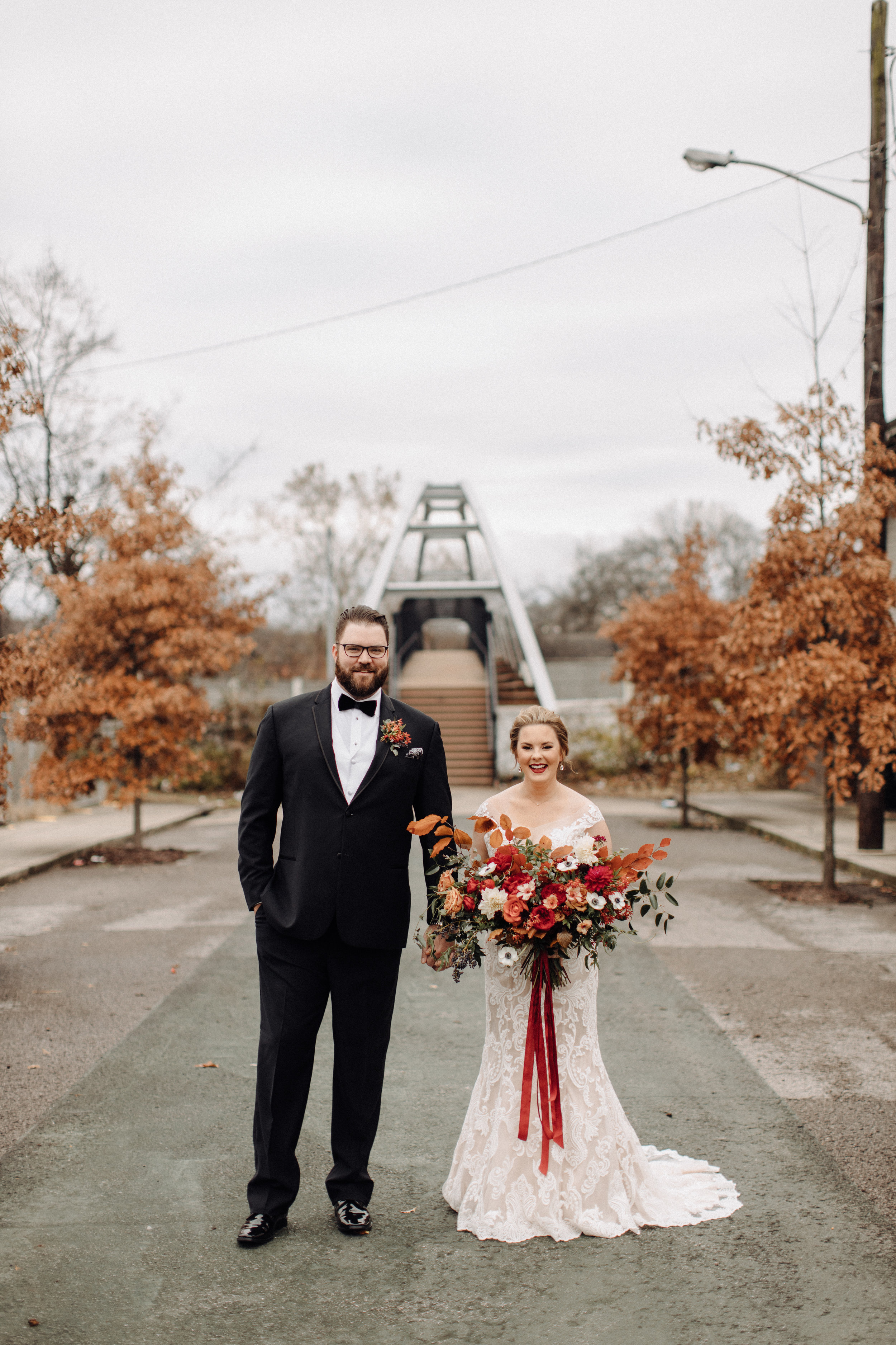 Asymmetrical, airy bridal bouquet with burgundy, burnt orange, and gold hues, using anemones, dahlias, and garden roses. Nashville, TN wedding florist.