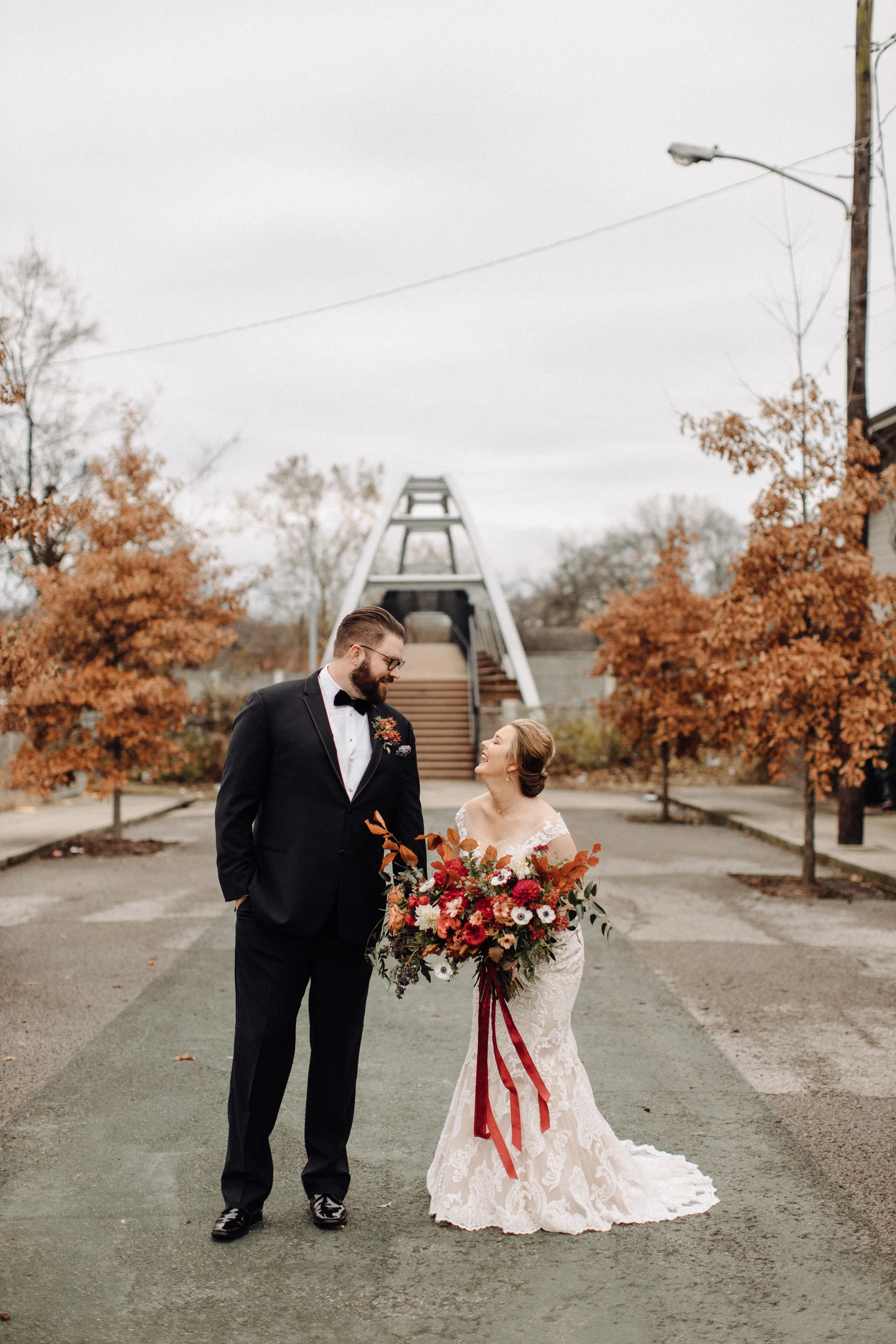 Asymmetrical, airy bridal bouquet with burgundy, burnt orange, and gold hues, using anemones, dahlias, and garden roses. Nashville, TN wedding florist.