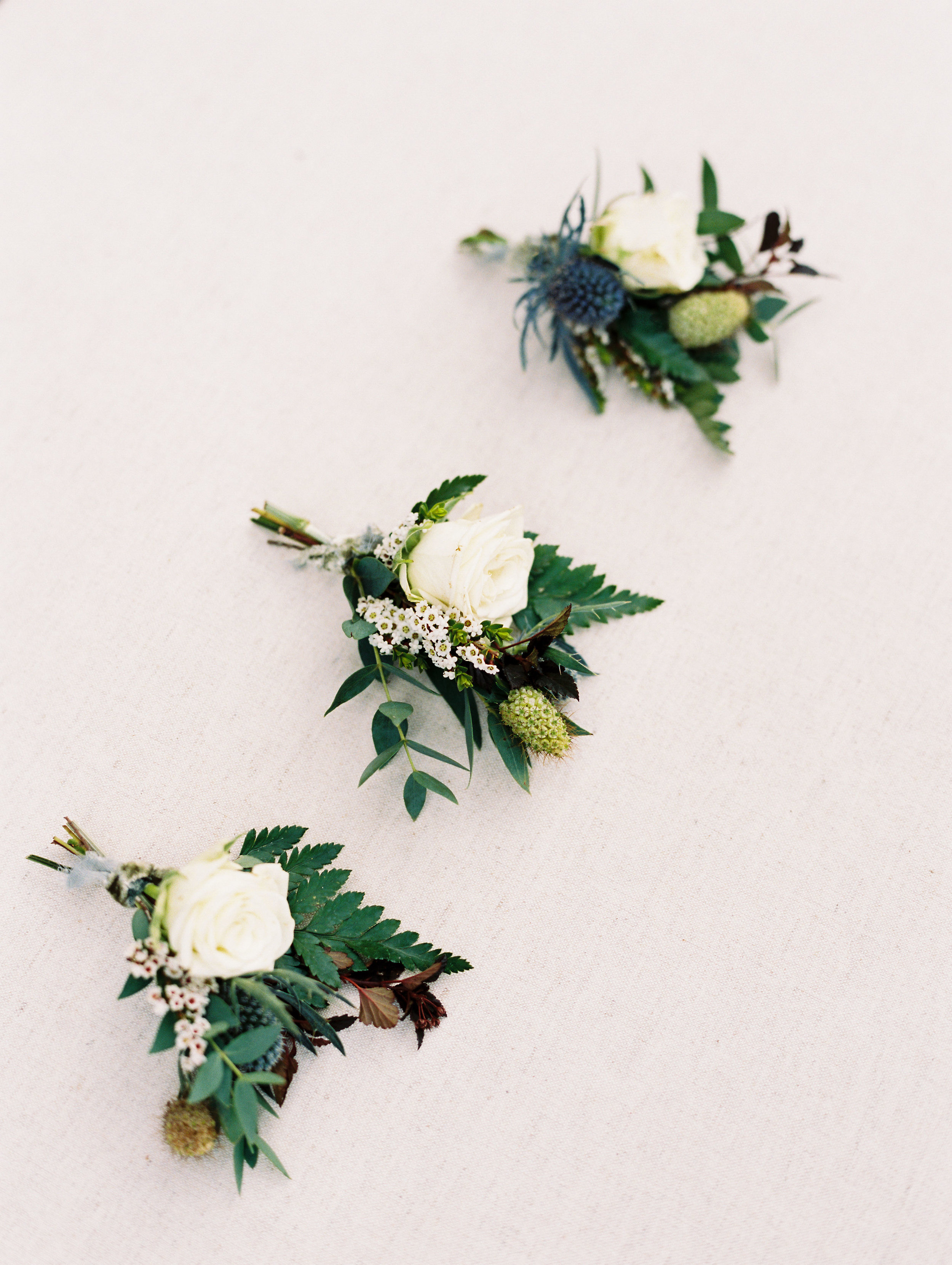 Texture boutonnieres with blue thistles and greenery. Destination Wedding Floral Design