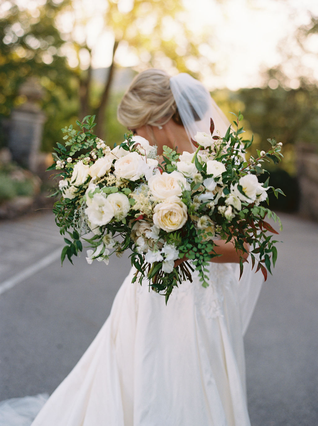 Untamed, asymmetrical bride’s bouquet with all white flowers and natural greenery. Southeast US Wedding Floral Design.