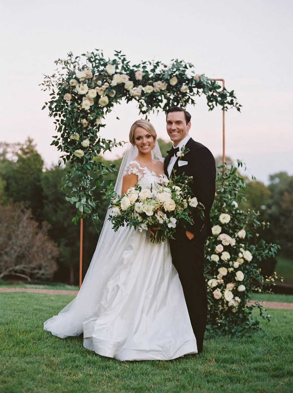 Modern copper arch with lush, garden-inspired florals and greenery. Cheekwood Wedding Flowers.