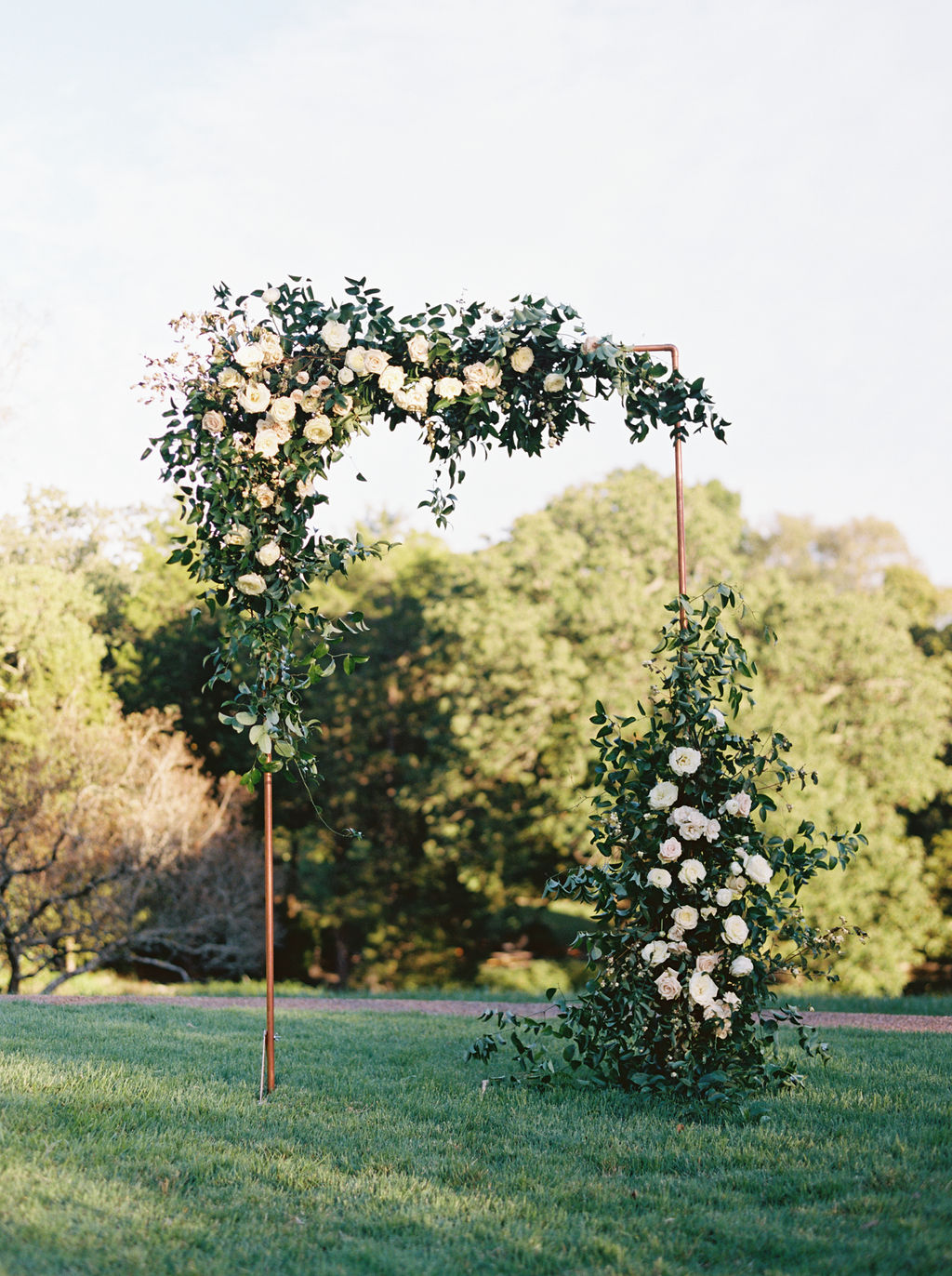 Modern copper arch with lush, garden-inspired florals and greenery. Cheekwood Wedding Flowers.