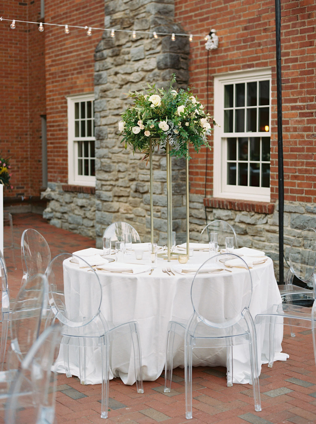 Modern gold stands overflowing with natural greenery and white floral centerpieces. Southeast US Wedding Floral Designer
