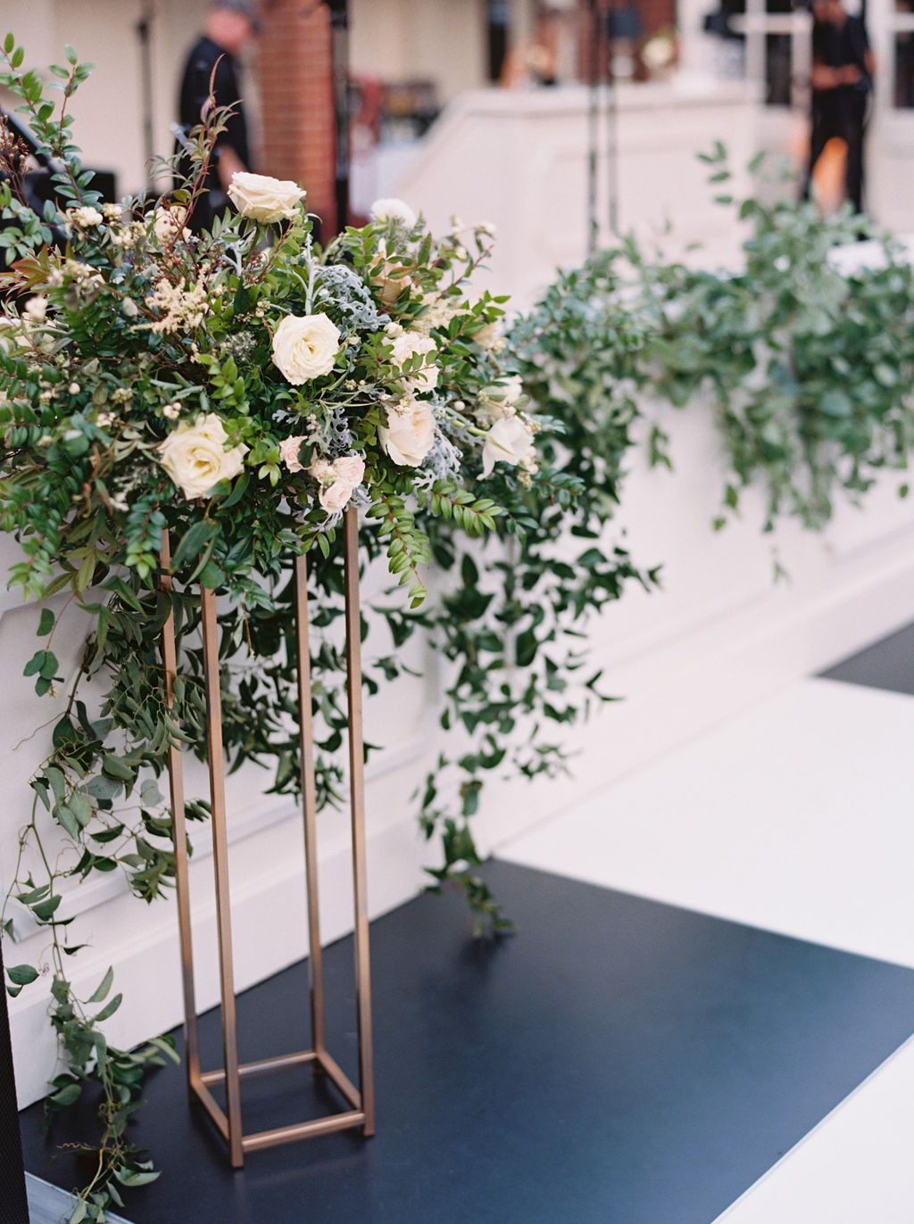 Modern gold stands overflowing with natural greenery and white floral centerpieces. Southeast US Wedding Floral Designer