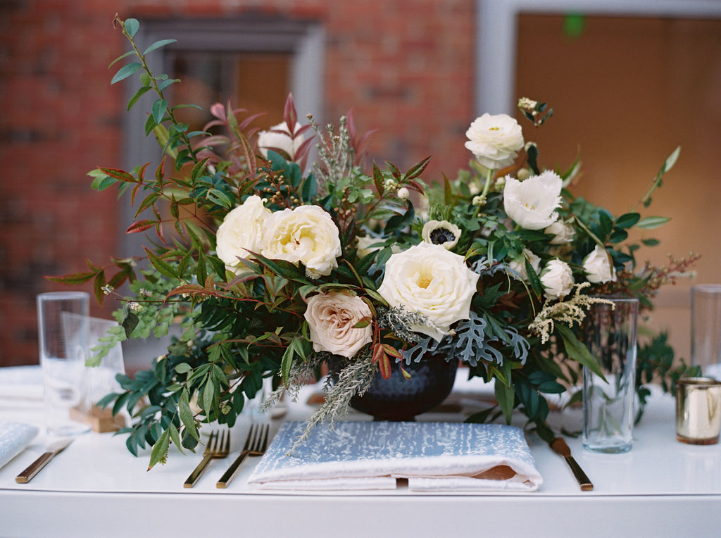 Low centerpiece with white and blush garden roses and ranunculus with natural greenery. Southeastern Wedding Floral Design