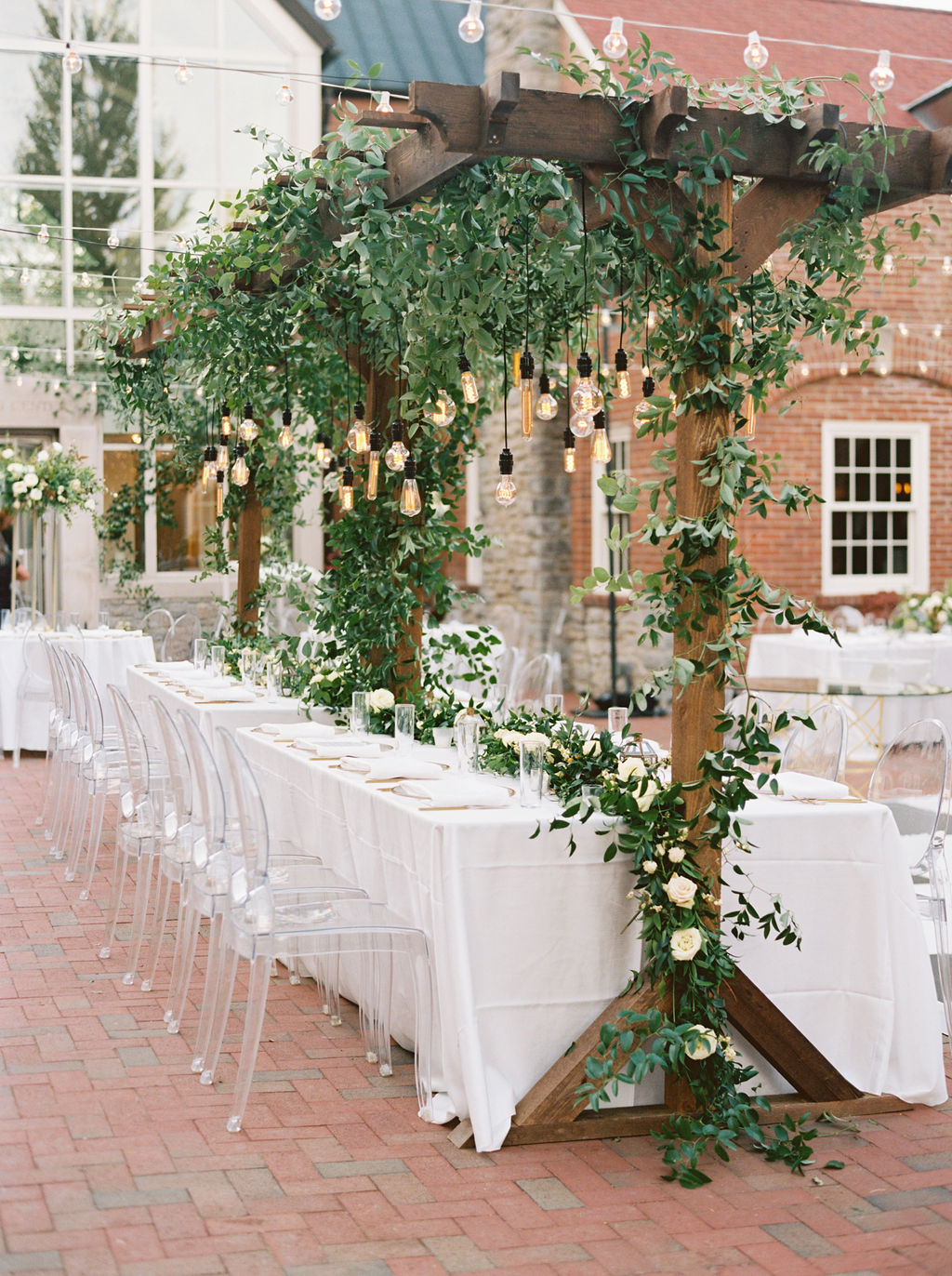 Wooden garden trellis over the head table with natural, vine-like greenery and floral garlands. Nashville Wedding Florist.