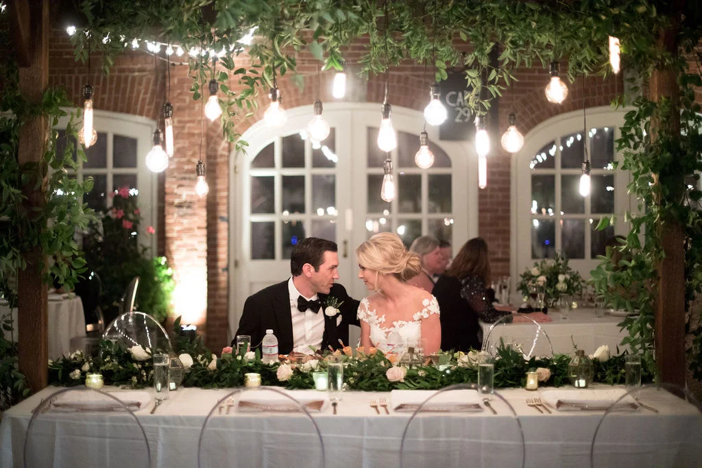 Wooden garden trellis over the head table with natural, vine-like greenery and floral garlands. Nashville Wedding Florist.