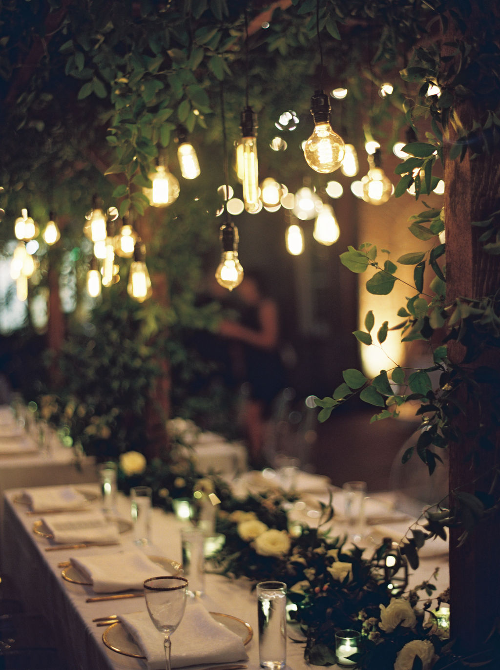 Wooden garden trellis over the head table with natural, vine-like greenery and floral garlands. Nashville Wedding Florist.