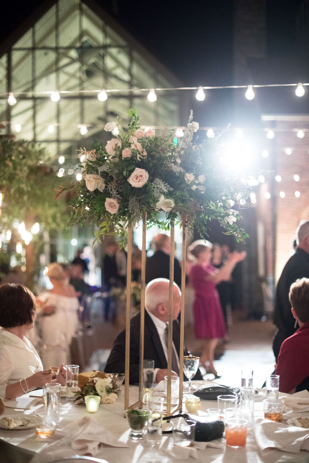 Modern gold stands overflowing with natural greenery and white floral centerpieces. Southeast US Wedding Floral Designer