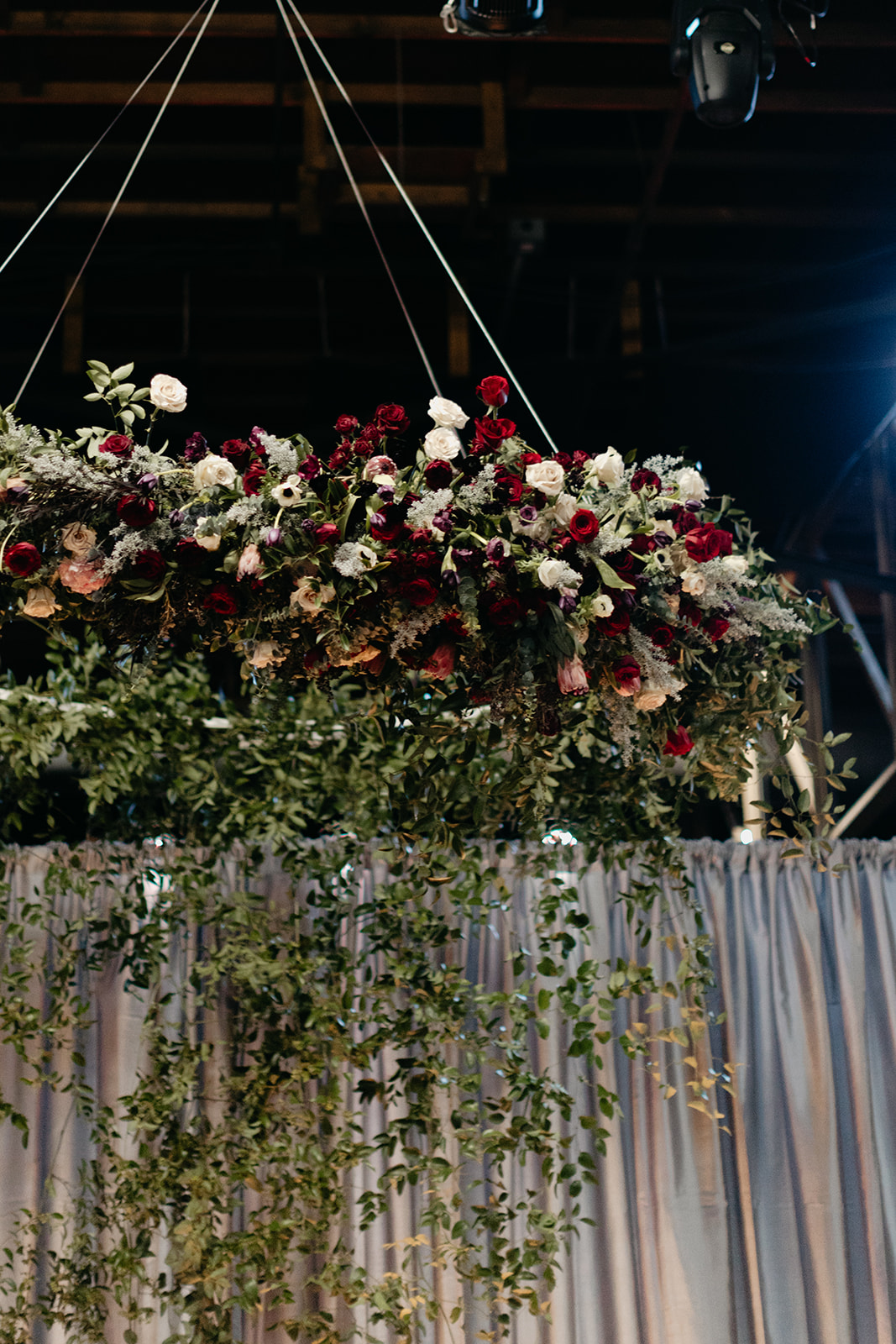 Oversized wreath floral installation with eggplant and burgundy florals and a curtain of greenery. Nashville Wedding Floral Design.