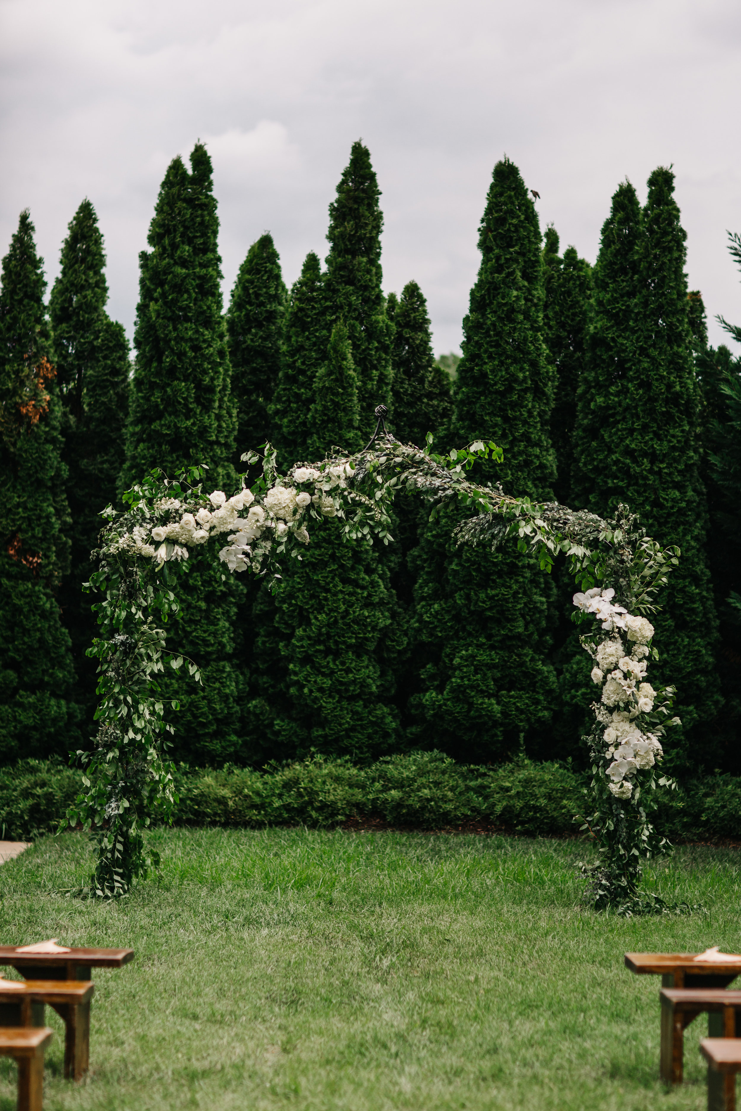 Lush garden arch for the ceremony backdrop with all white orchids, garden roses, and ranunculus. Southeastern US floral design for weddings.