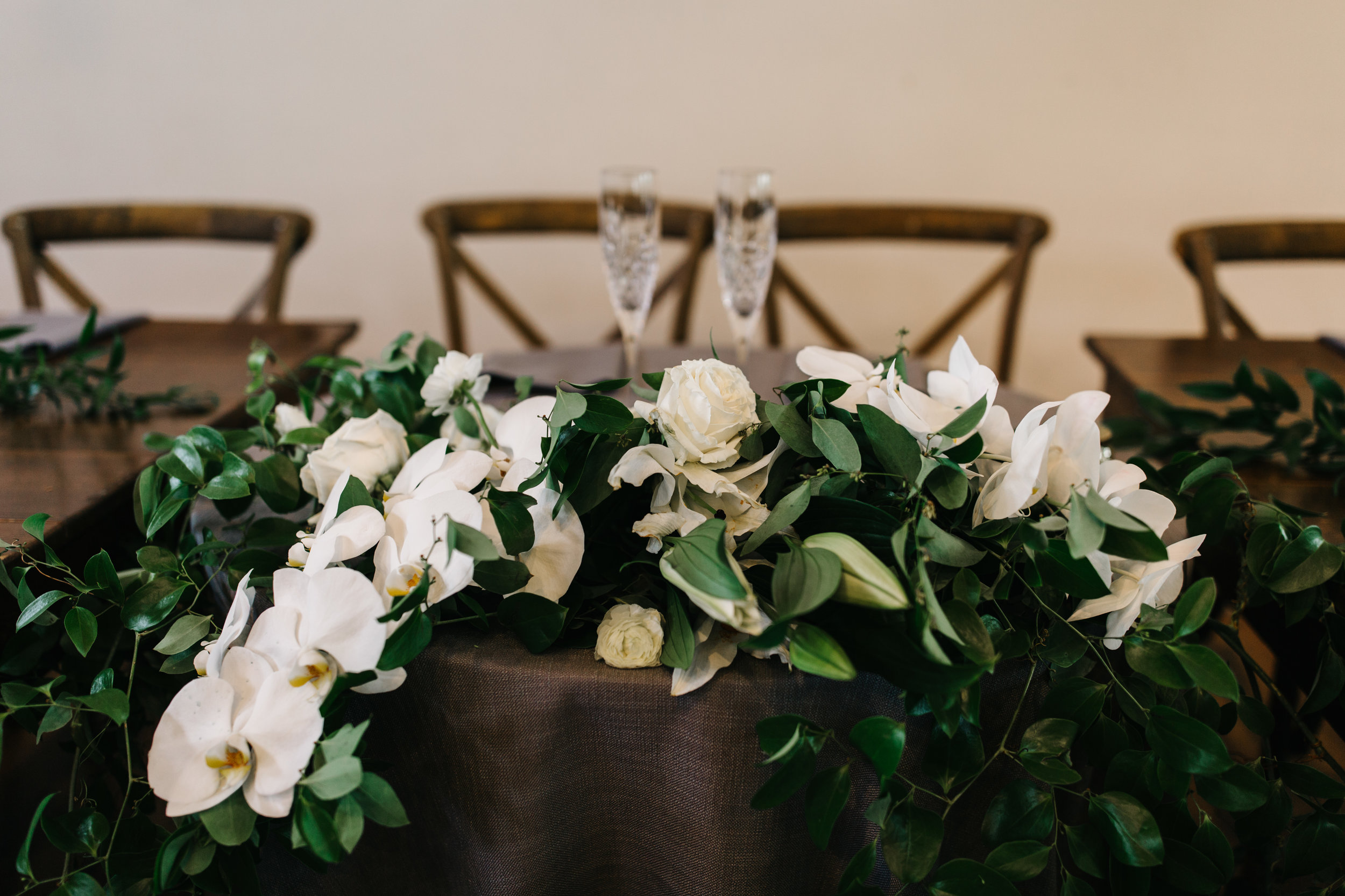 Romantic, flower covered sweetheart table with a cascading garland of orchids and garden roses. Nashville Wedding Floral Design.