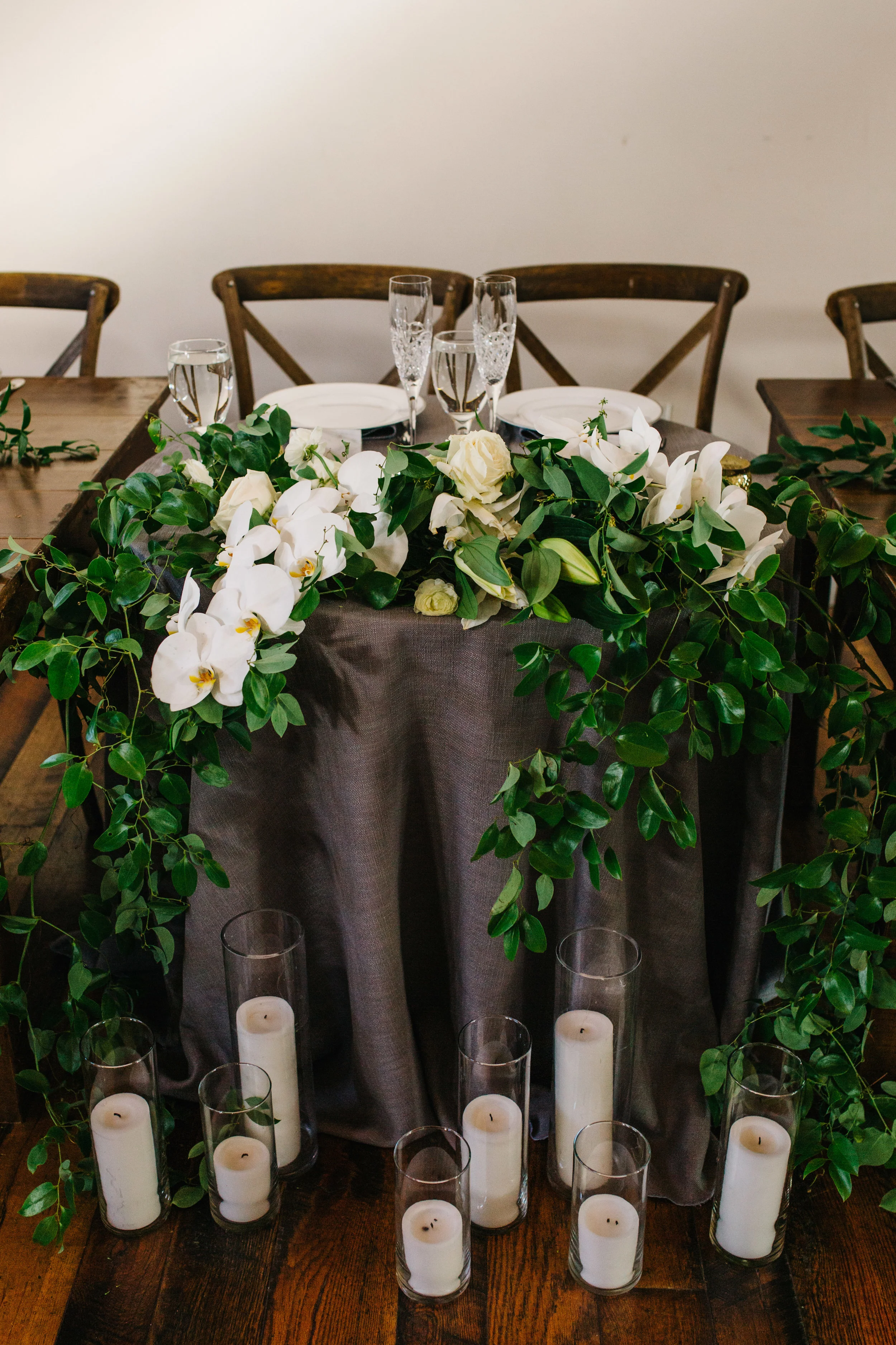 Romantic, flower covered sweetheart table with a cascading garland of orchids and garden roses. Nashville Wedding Floral Design.