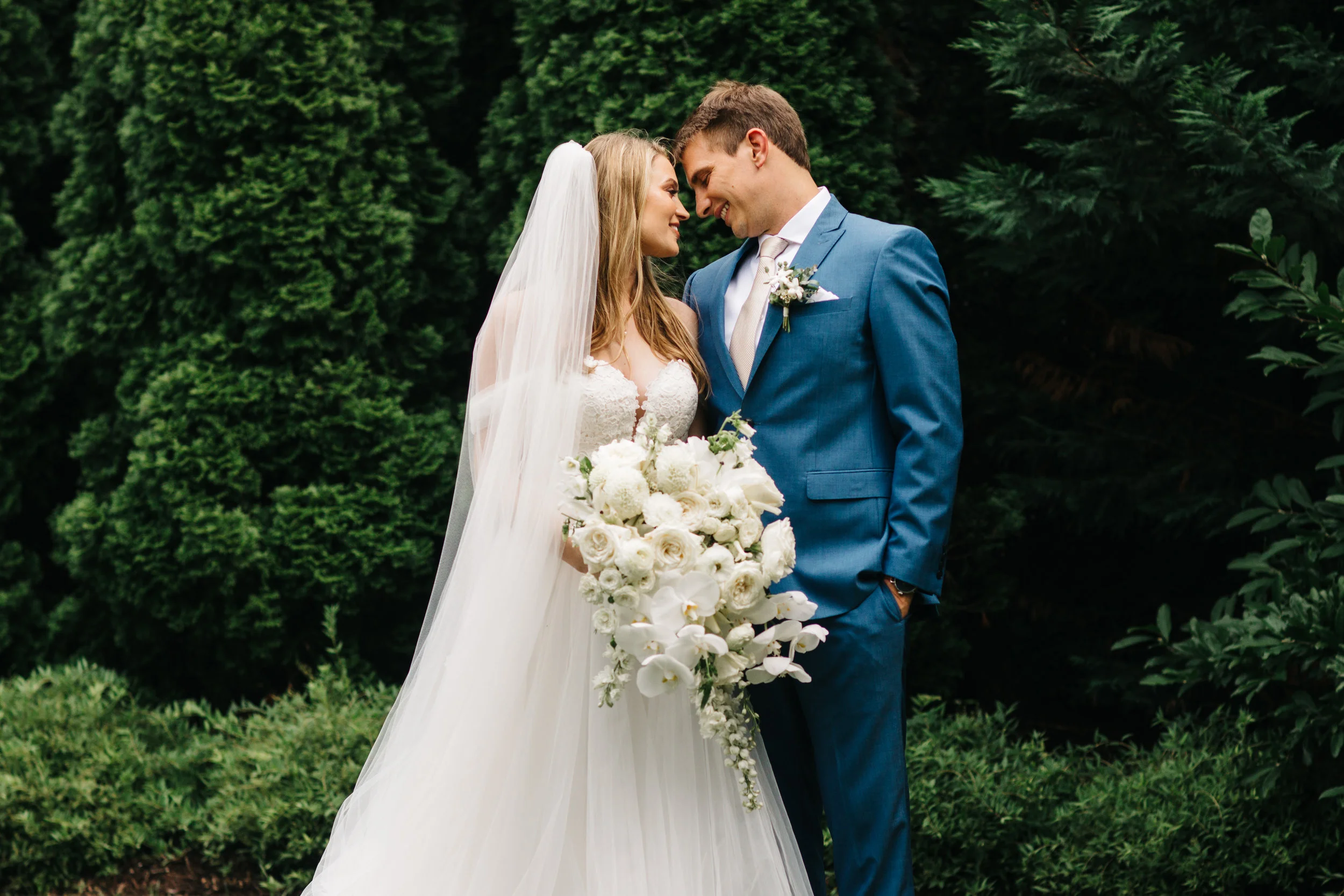 All white, cascading bridal bouquet with orchids, garden roses, and ranunculus. Nashville Wedding floral design at the Cordelle.