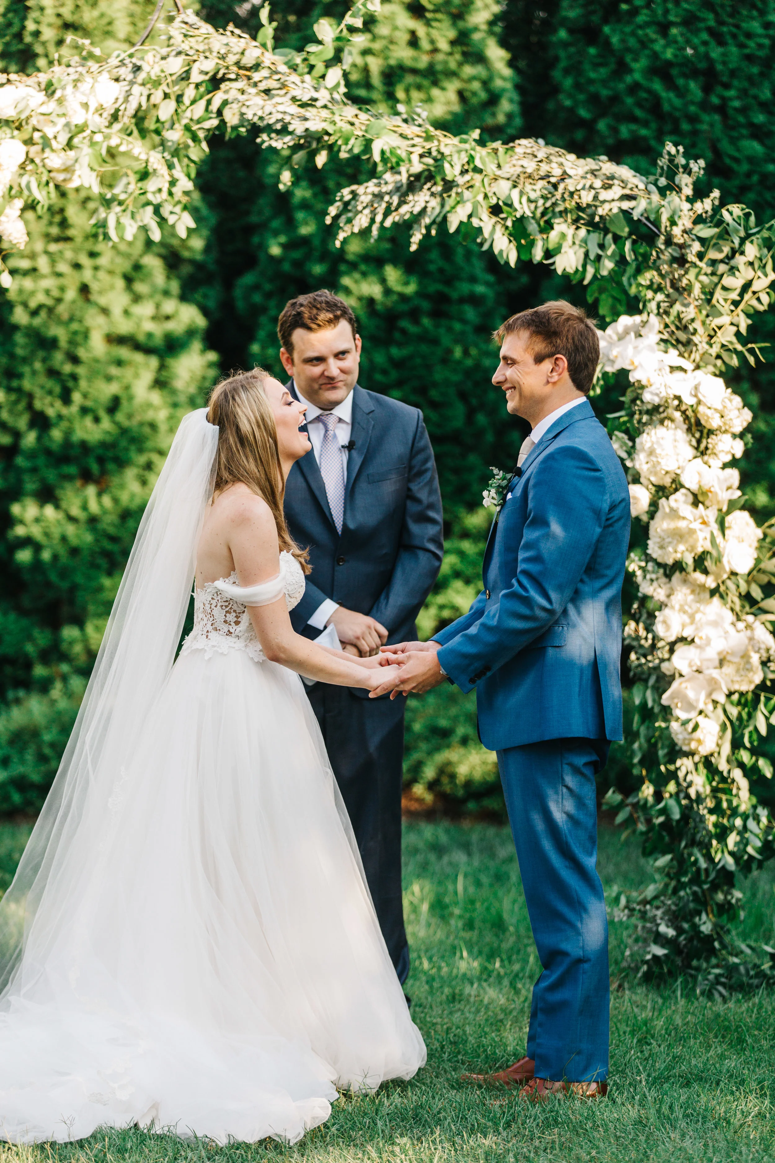 Lush garden arch for the ceremony backdrop with all white orchids, garden roses, and ranunculus. Southeastern US floral design for weddings.