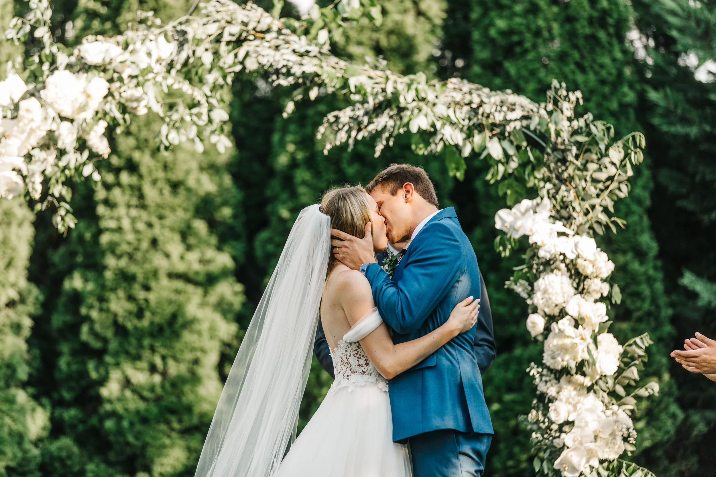 Lush garden arch for the ceremony backdrop with all white orchids, garden roses, and ranunculus. Southeastern US floral design for weddings.