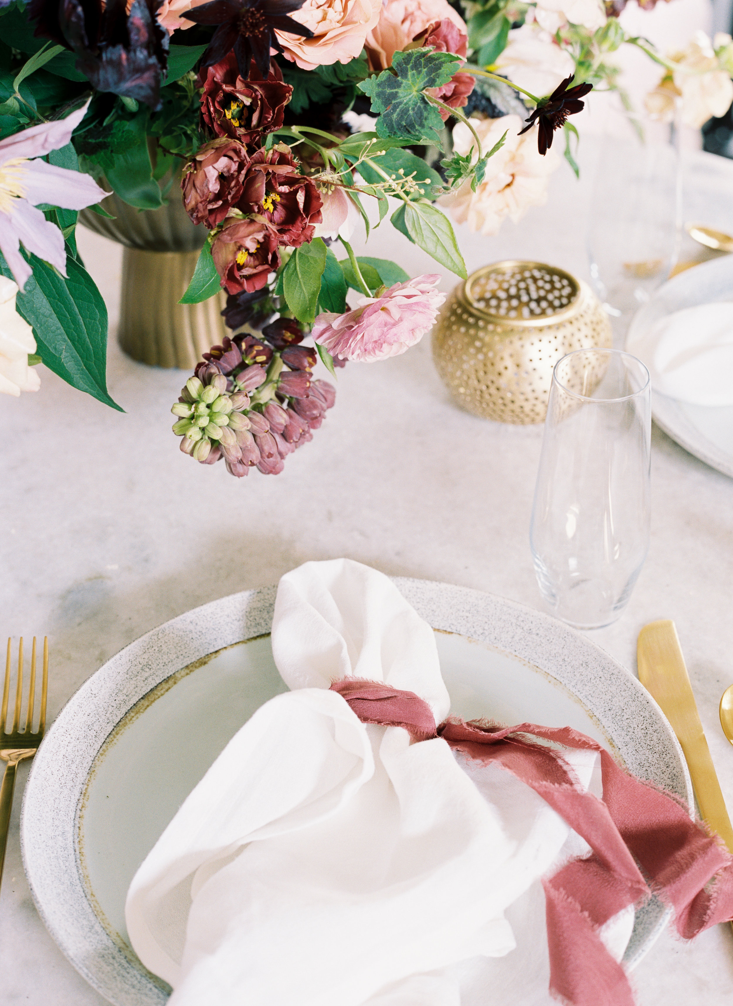 Gold flatware, rusty rose silk ribbon, and marble tabletop. April wedding flowers inspiration from a Nashville florist, Rosemary & Finch.