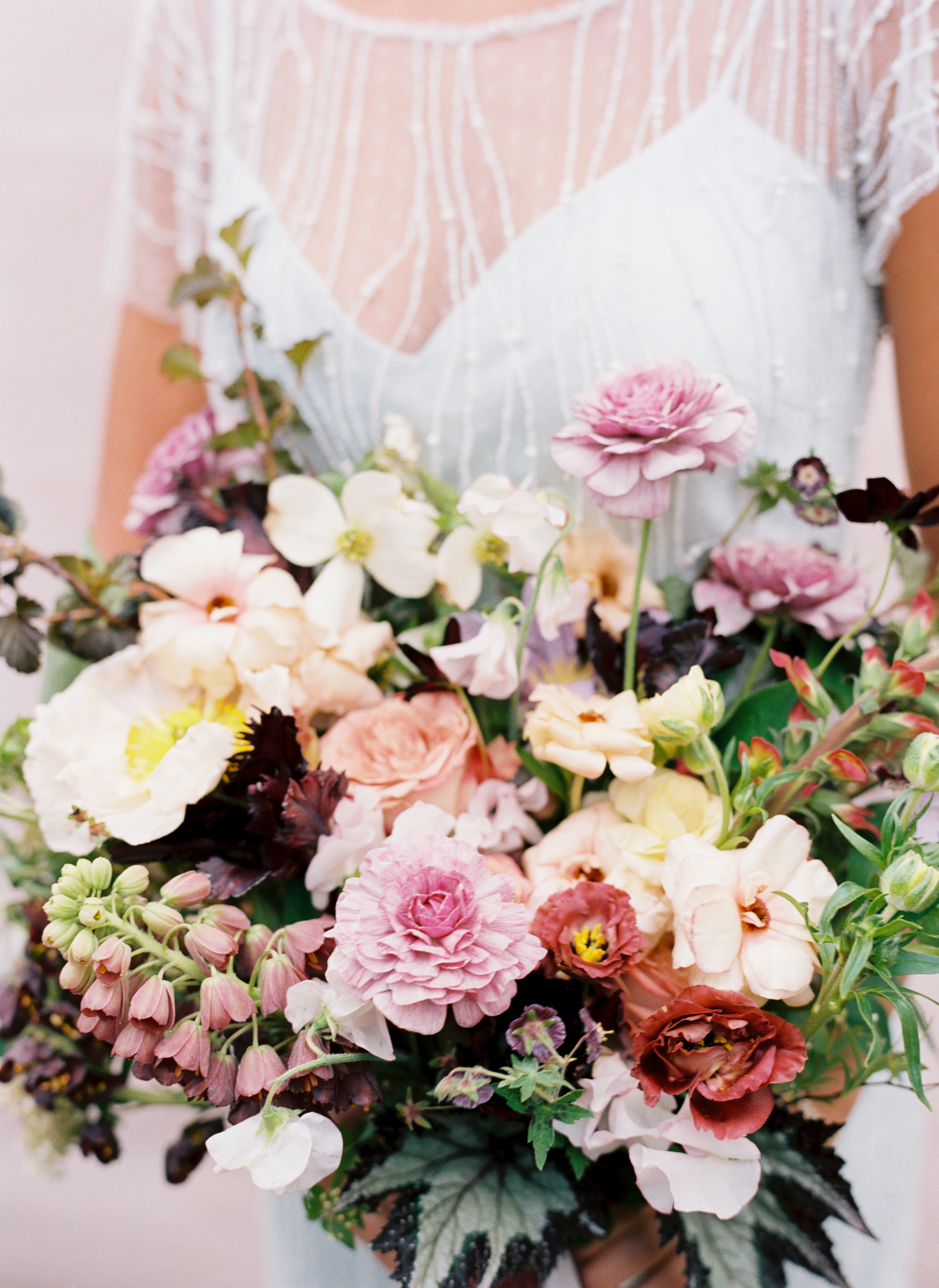 Spring bridal bouquet composed of mauve ranunculus, butterfly ranunculus, fritillaria, Icelandic poppies, sweet peas, and organic greenery. Nashville Wedding Floral Design.