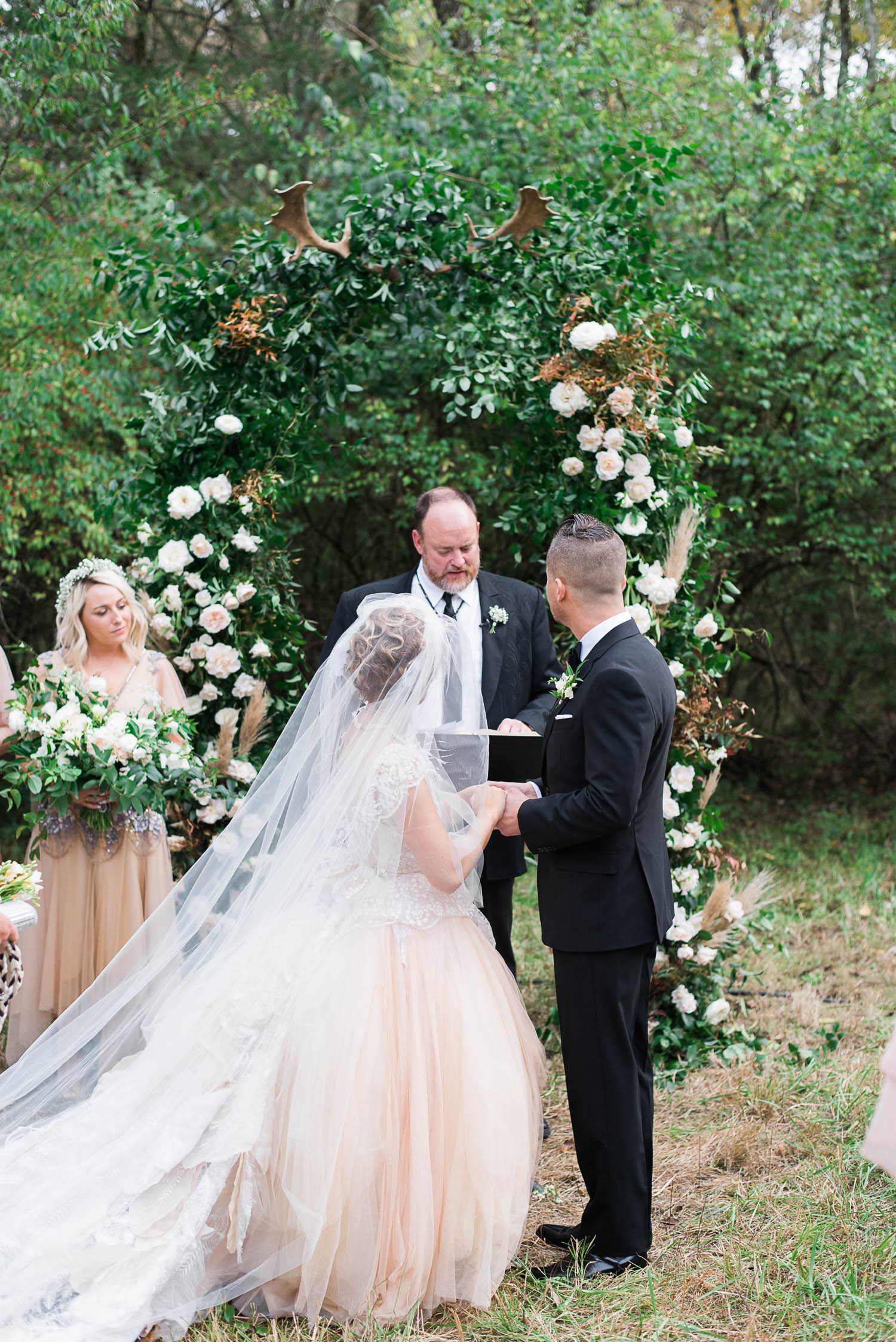 Lush wedding arch with greenery, garden roses, and antlers. Nashville Wedding Floral Design.