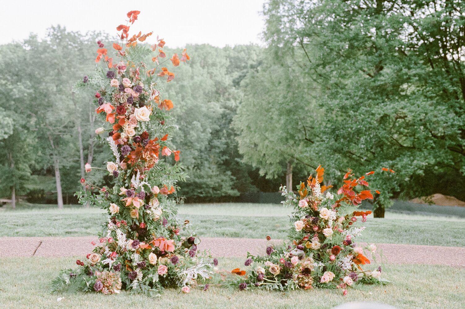 Freestanding wedding ceremony backdrop with lush greenery and a bright flowers. Nashville wedding floral design by Rosemary & Finch.