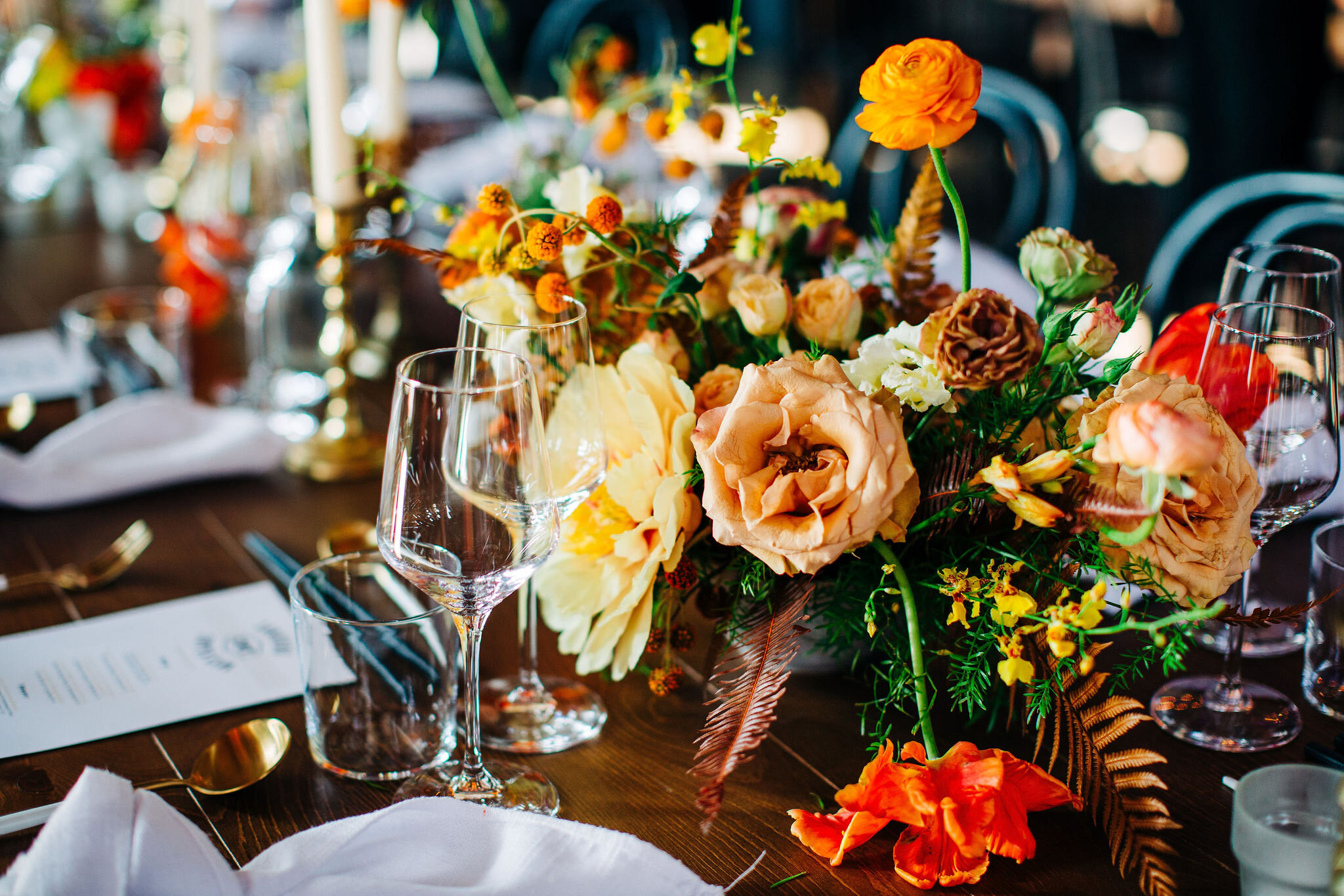Yellow peonies, orange ranunculus, and golden fern floral centerpieces. Nashville wedding florist.