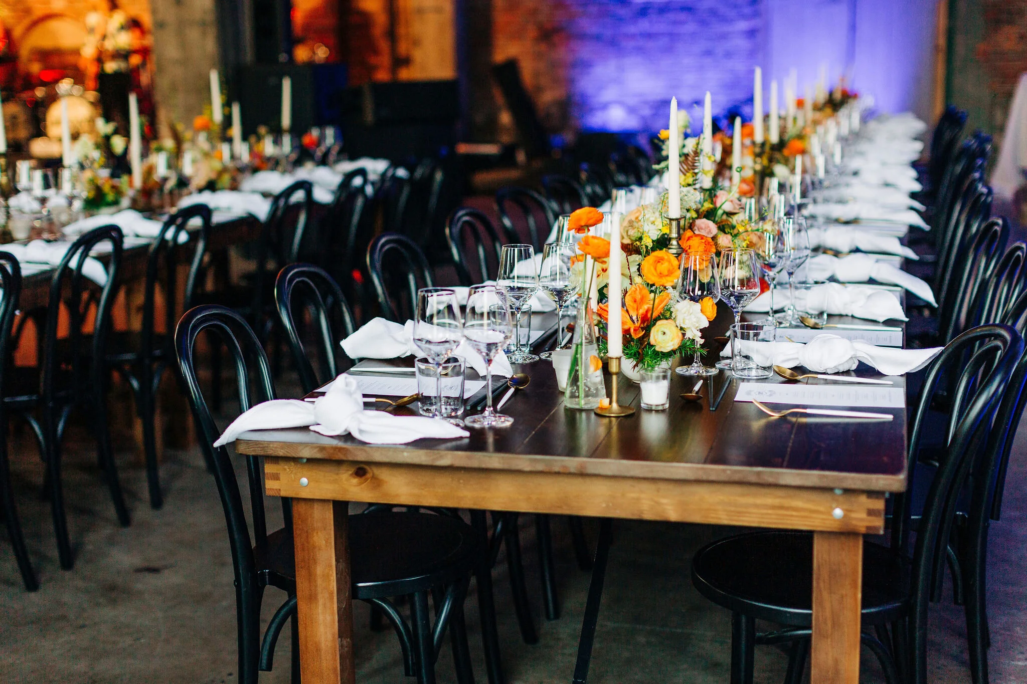 Yellow peonies, orange ranunculus, and golden fern floral centerpieces with brass candlesticks. Nashville wedding florist.
